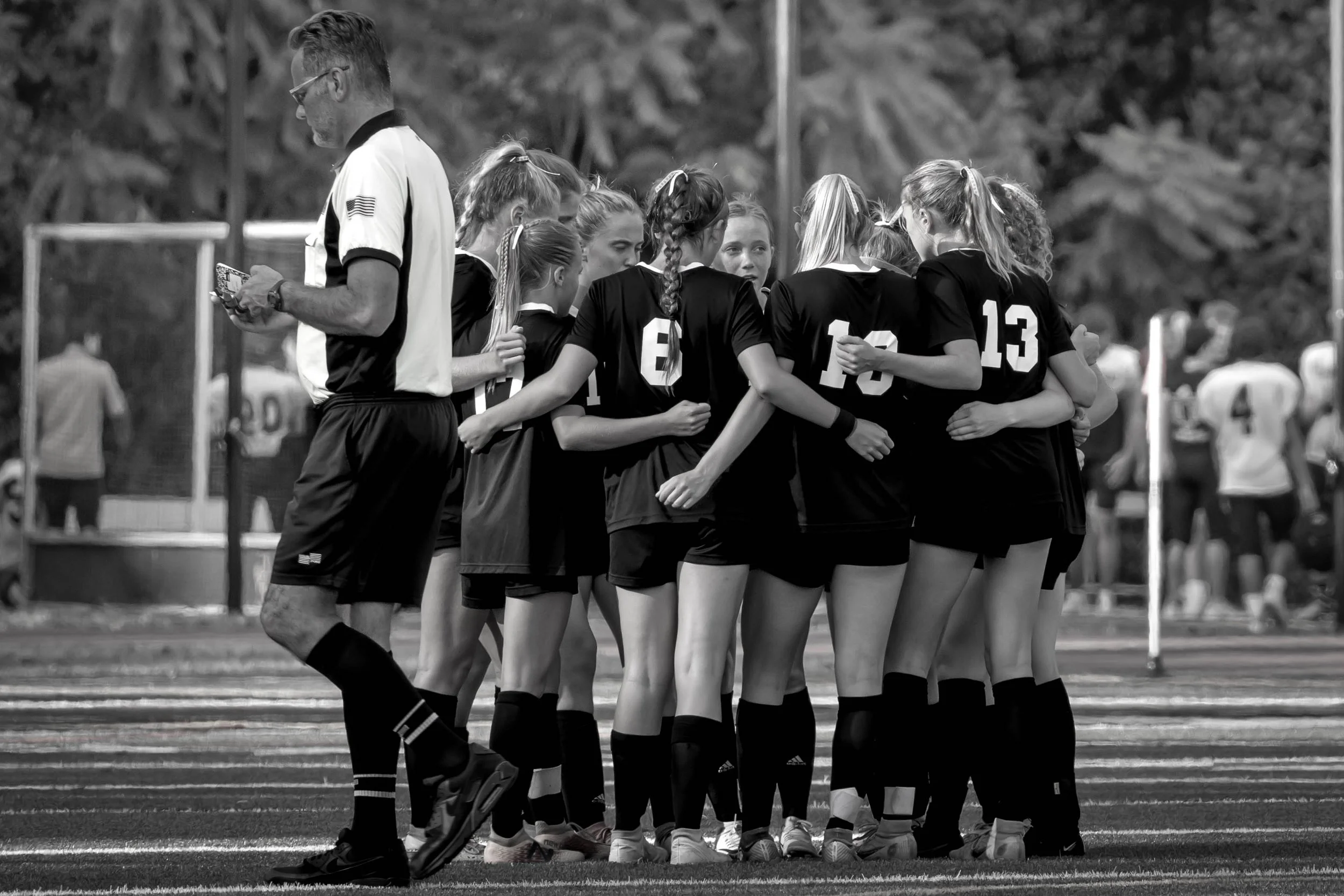 Candid team moment of a Haddonfield, NJ soccer team in a pre-game huddle, captured in artistic black and white.