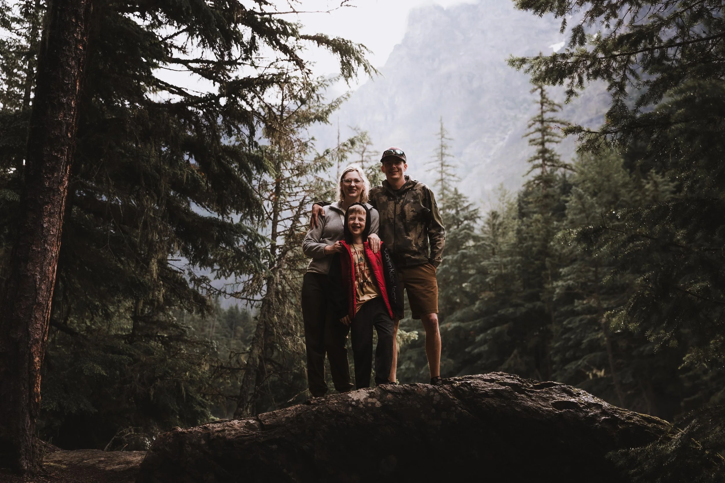 Family standing on rock overlooking forest and mountains during outdoor portrait