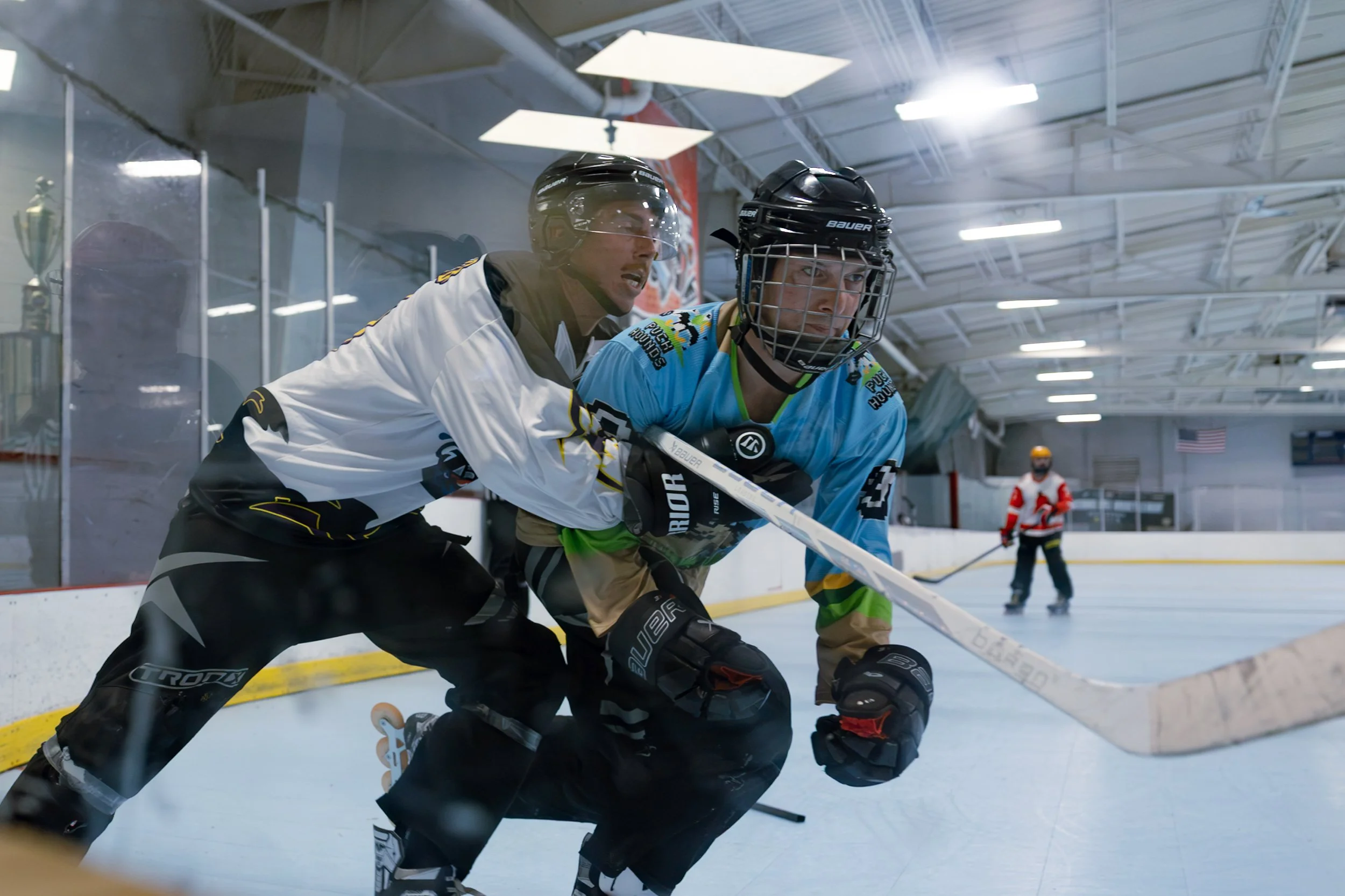 Two roller hockey players battling for the puck along the boards during a game at Choice Inline Arena in Pitman, New Jersey