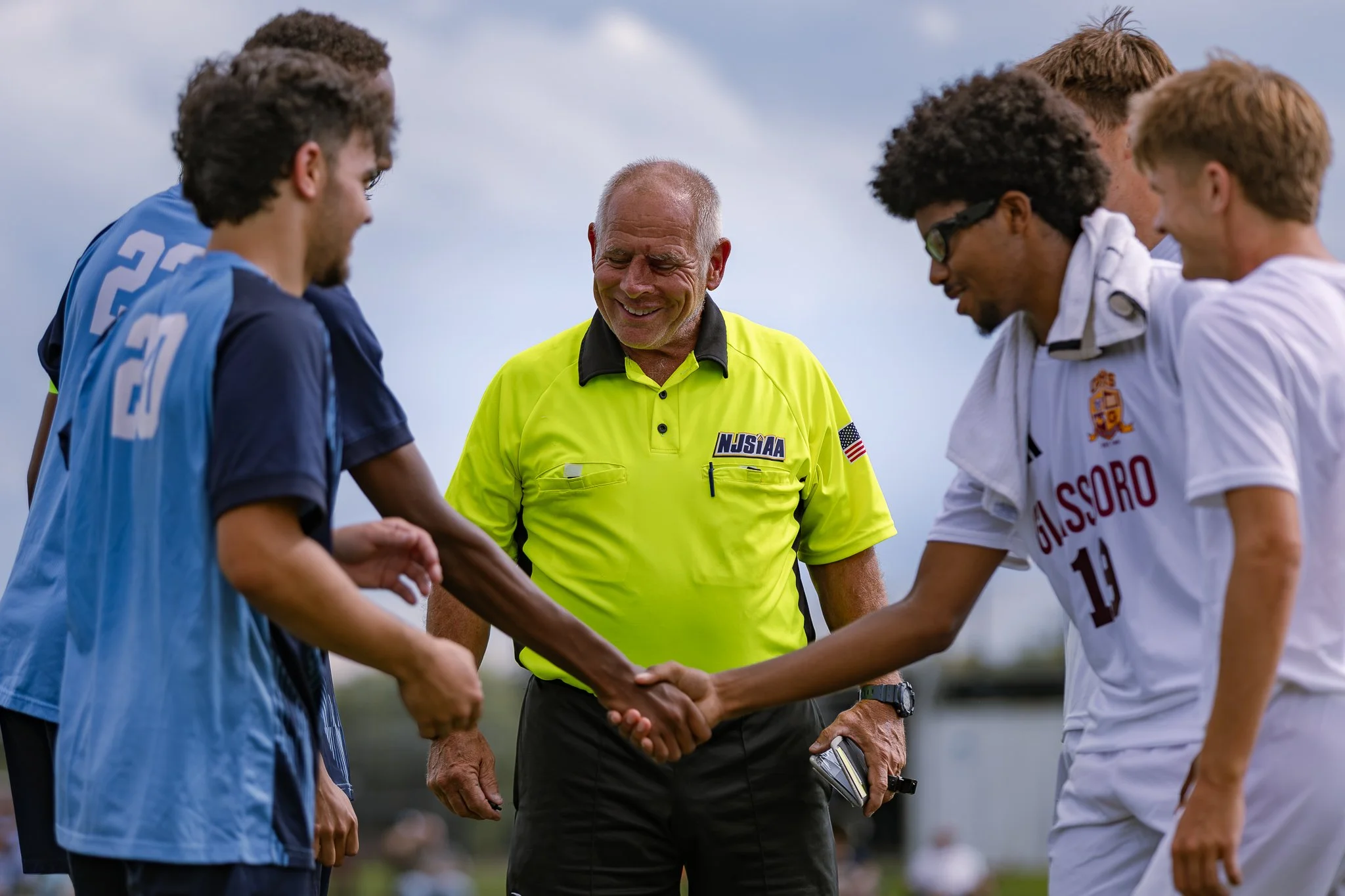 Players and officials shake hands in a display of sportsmanship prior to a Gloucester County high school soccer matchup.
