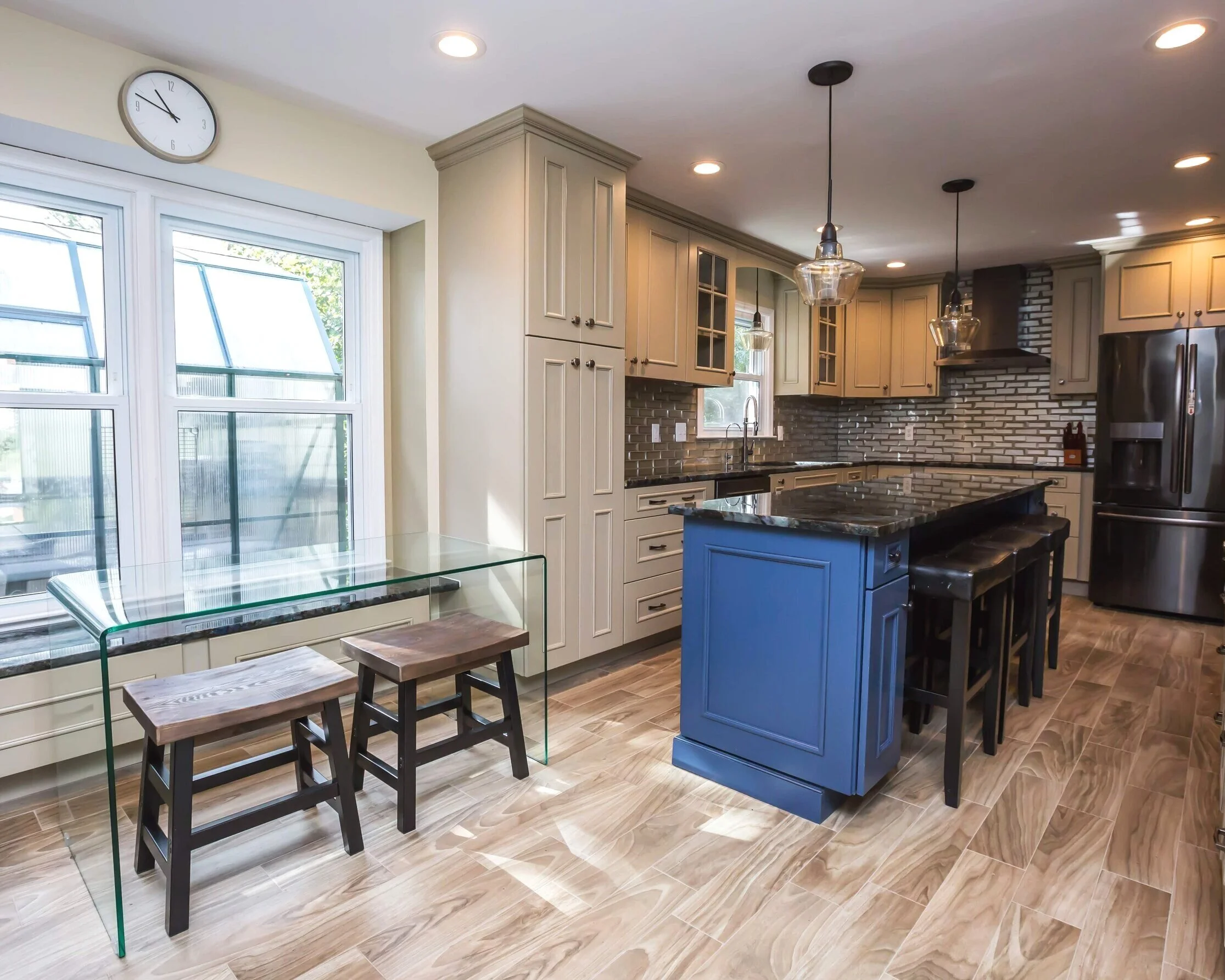 A view of the minimalist glass table with leather cushioned wooden stools and the greenhouse window. Check out the rustic wood floor!