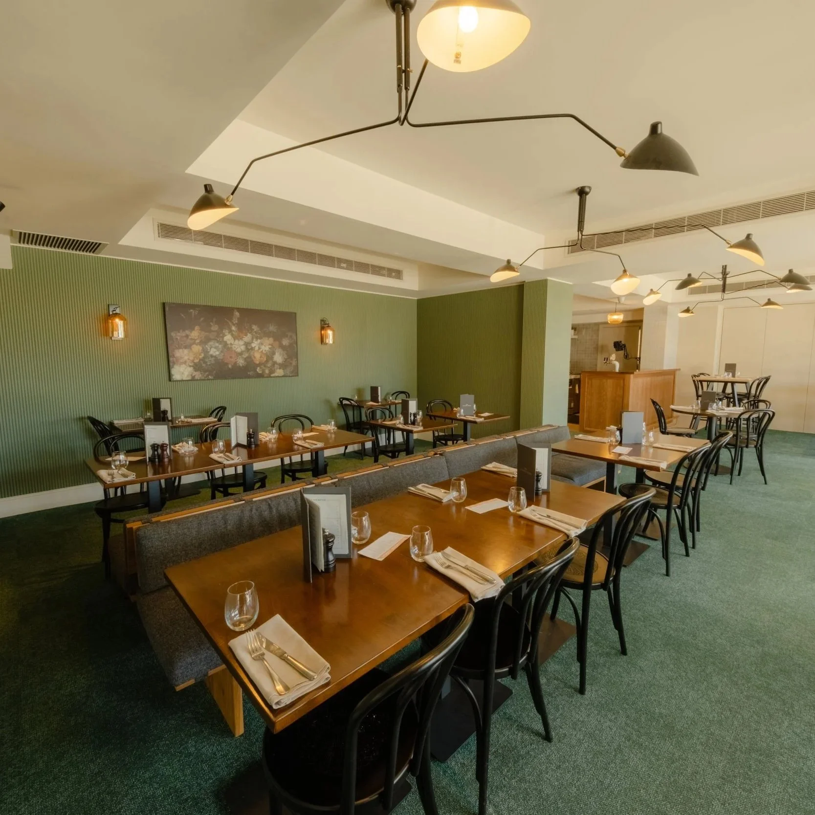 A Private Dining area with wooden tables, black chairs, wine glasses, and napkins set on the tables for a private function