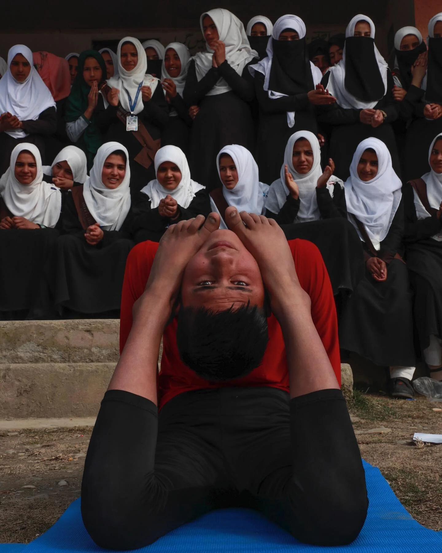 A Secondary School student in the Baramulla region of Kashmir performs yoga for myself and a small audience. From the archives, Jan 2020. 

Young men learn yoga as their physical fitness requirement. 
The women watch and applaud, as they are not allo