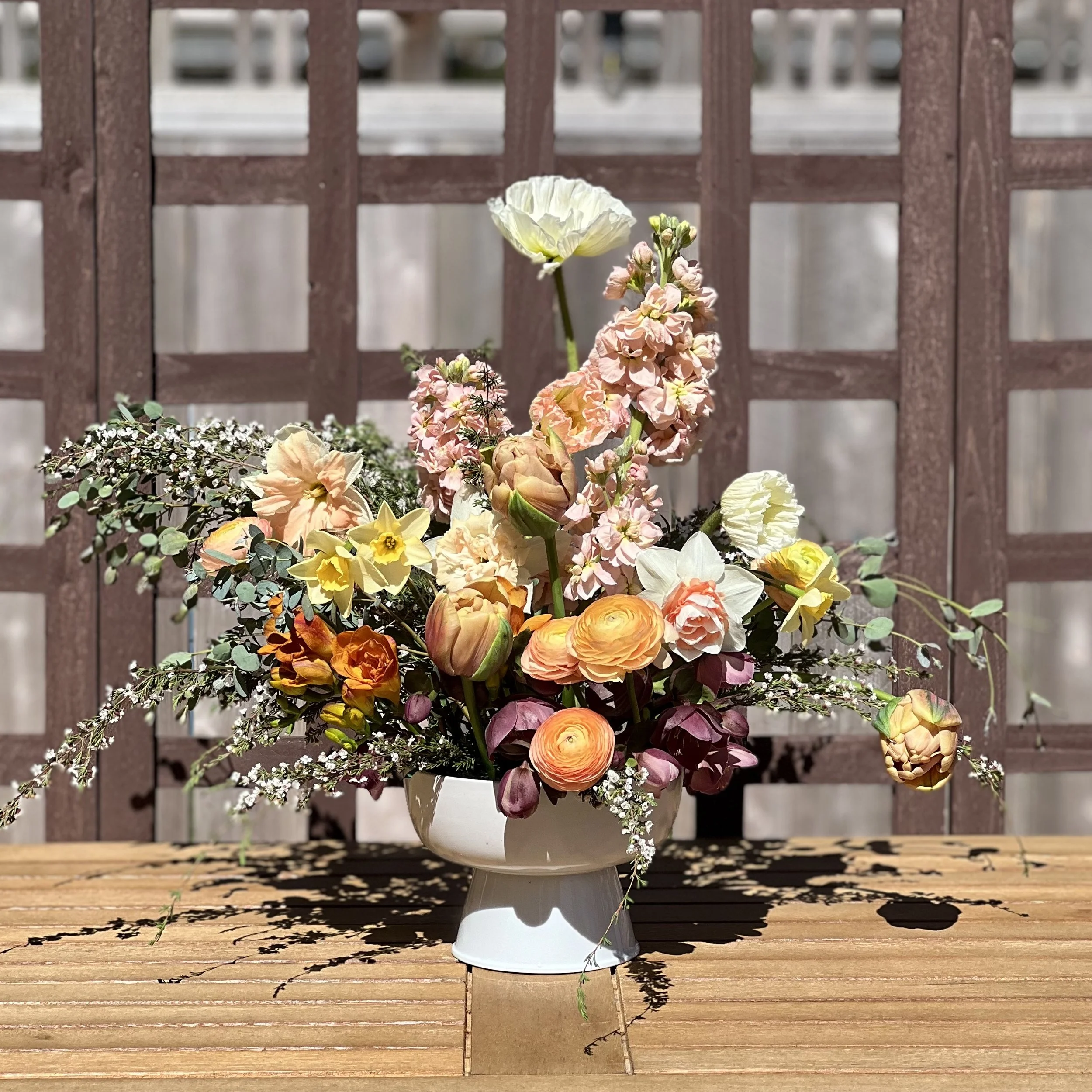 Spring compote with ranunculus, poppies, freesia, stock, and tulips
