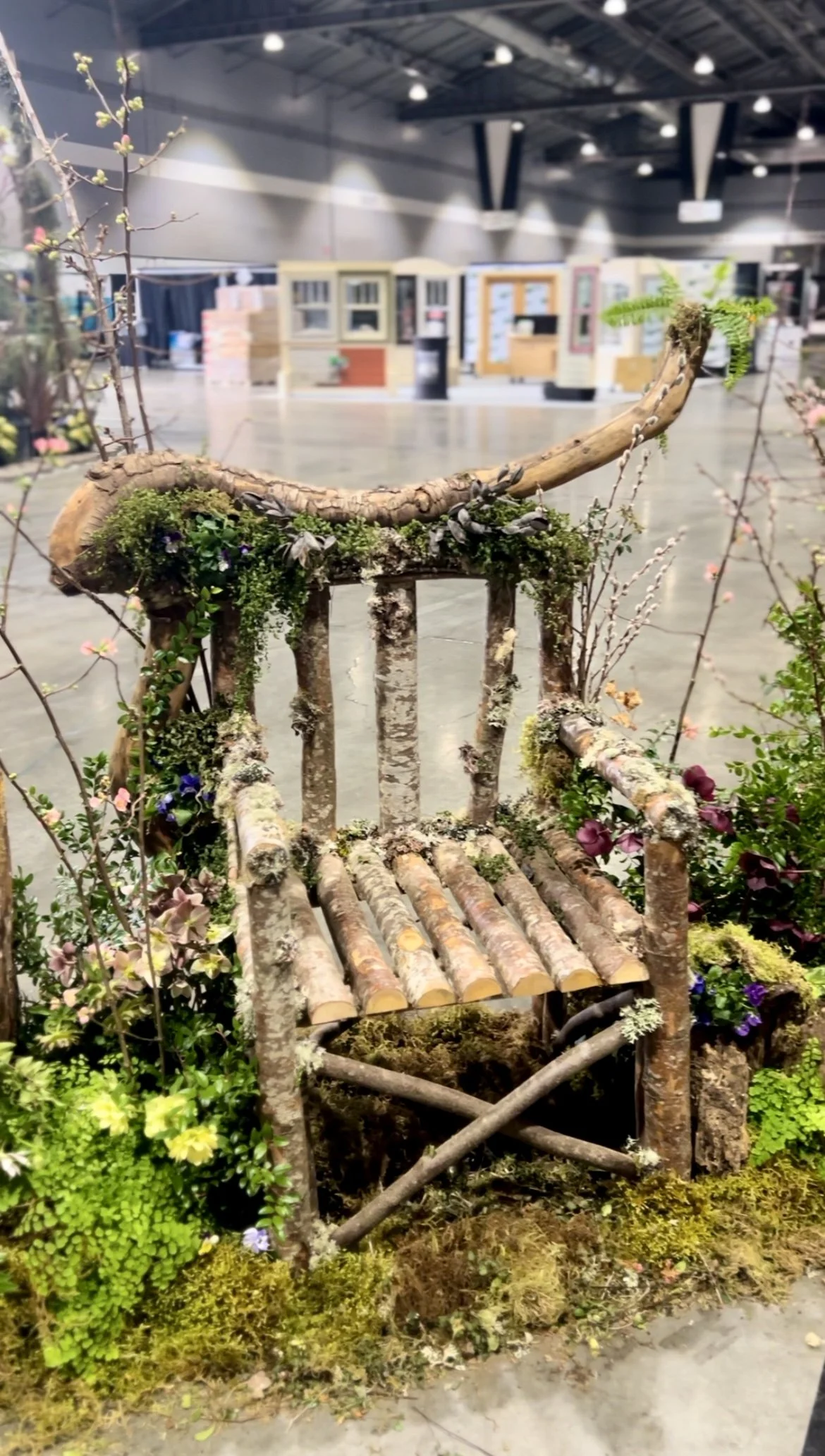 Wooden throne decorated with blooming branches, ferns, moss, pansies, and hellebore
