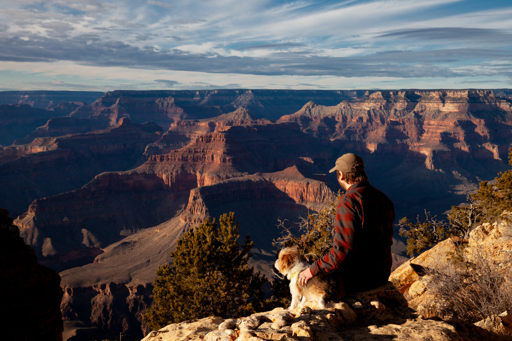 Man and dog sitting on rim of grand cayon