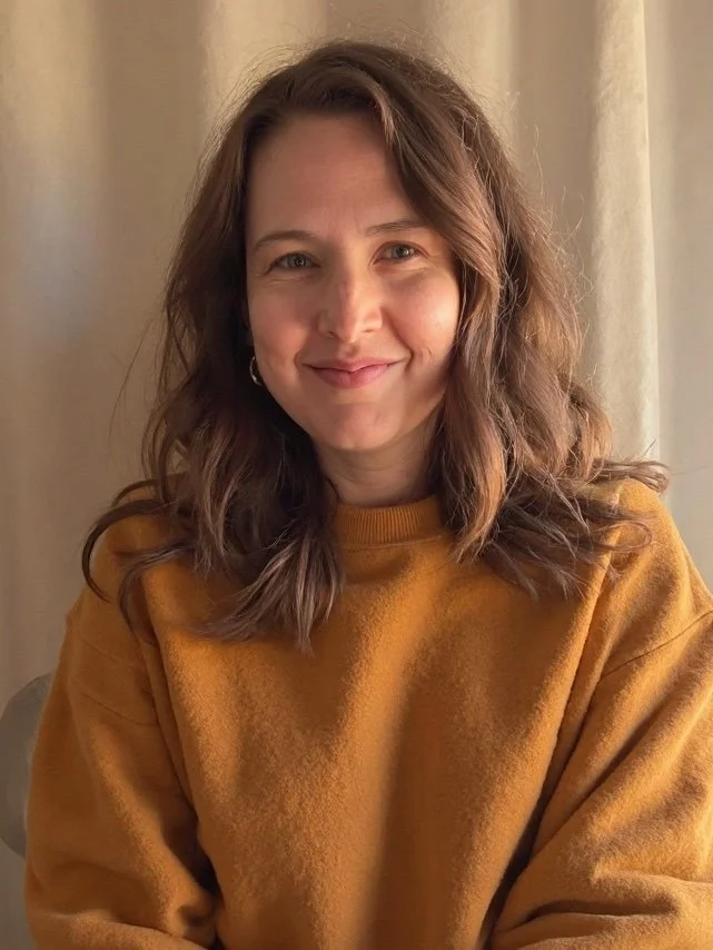 Picture of Ashley smiling with a beige curtain behind her