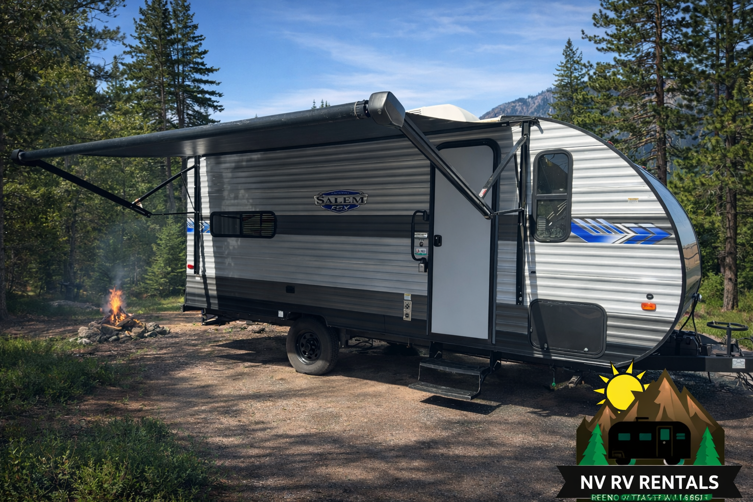 A travel trailer parked in a wooded area with a campfire burning nearby, and a mountain and trees in the background.