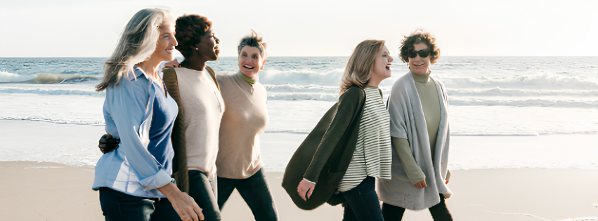 Group of five women walking and talking on the beach during sunset.