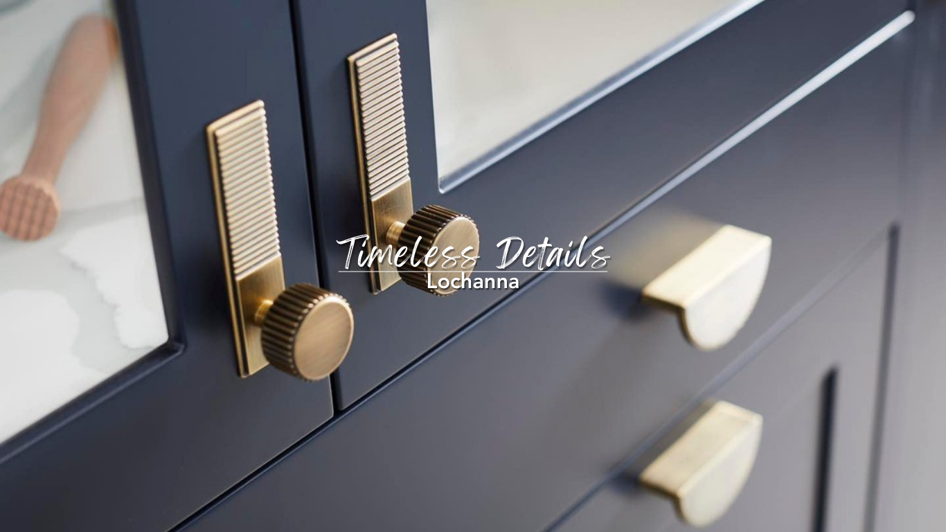 Close-up of dark navy cabinet doors with gold knobs and sliders, with a marble countertop and a child's foot in the background.