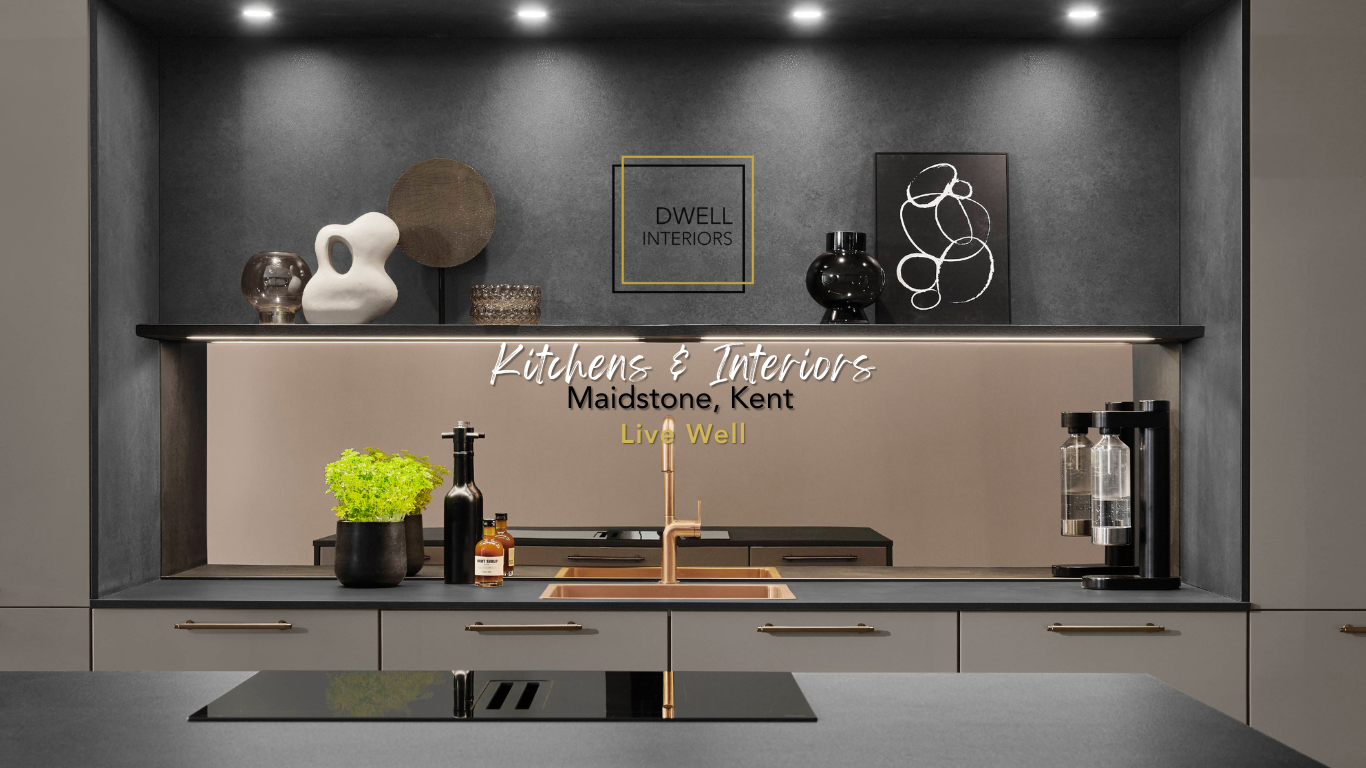 Modern kitchen with dark gray and beige cabinets, black countertop, copper faucet, decorative vases and art on the wall, and under-cabinet lighting.
