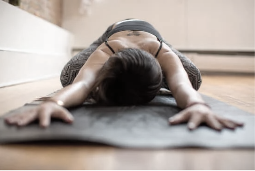 Person performing a yoga pose on a mat in a home setting.