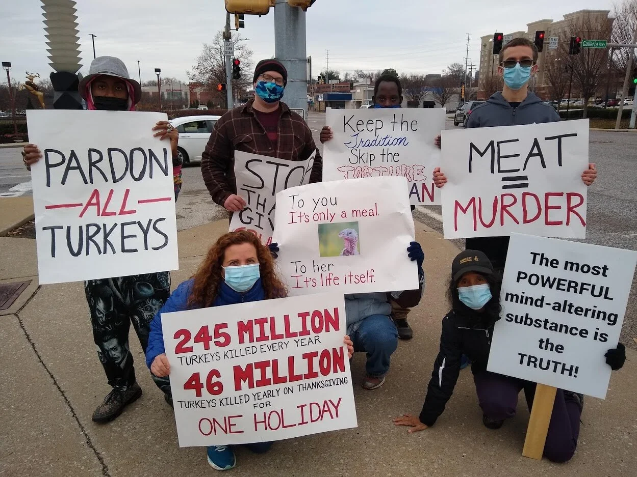Group picture with several animal rights activists holding their signs urging people to go vegan.jpg