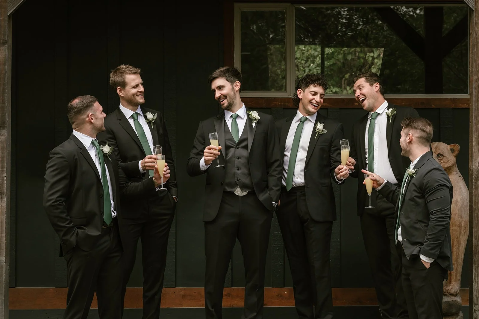  A groom and a group of men standing around and chatting with each other.  