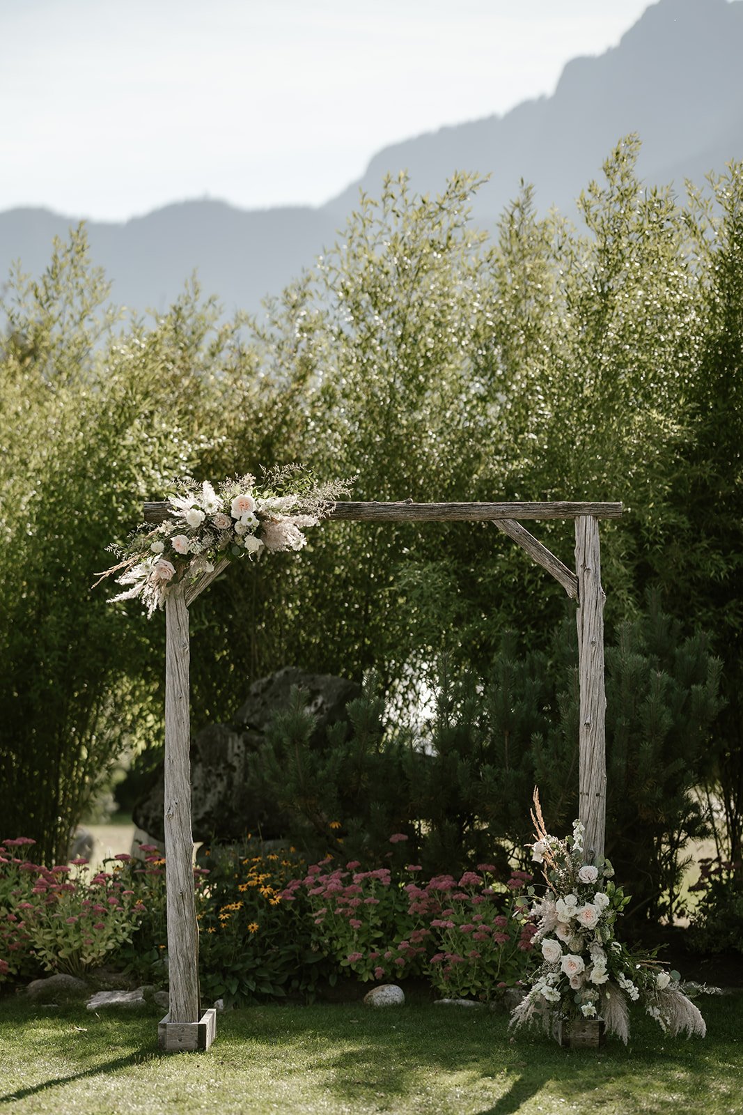  A wooden structure with flowers on it with trees and mountains behind.  