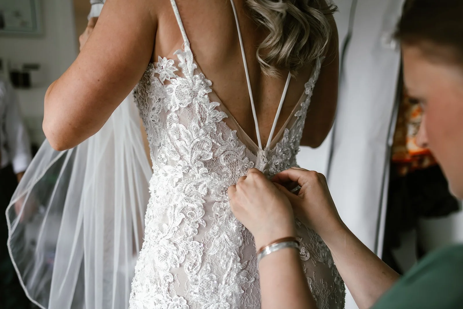  A bride getting ready with another woman clasping her dress on.  
