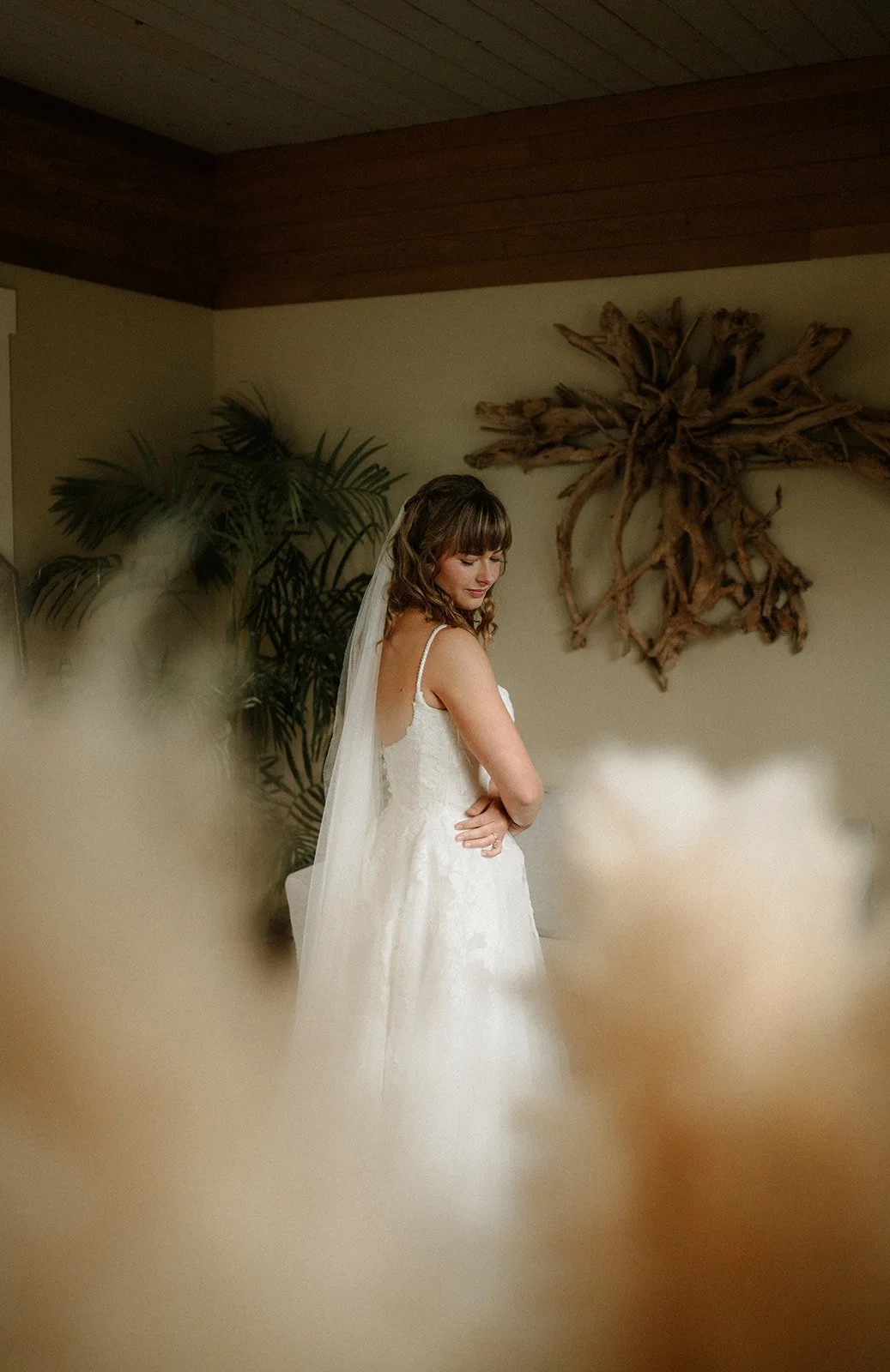  A bride standing in her wedding dress and veil in a room.  
