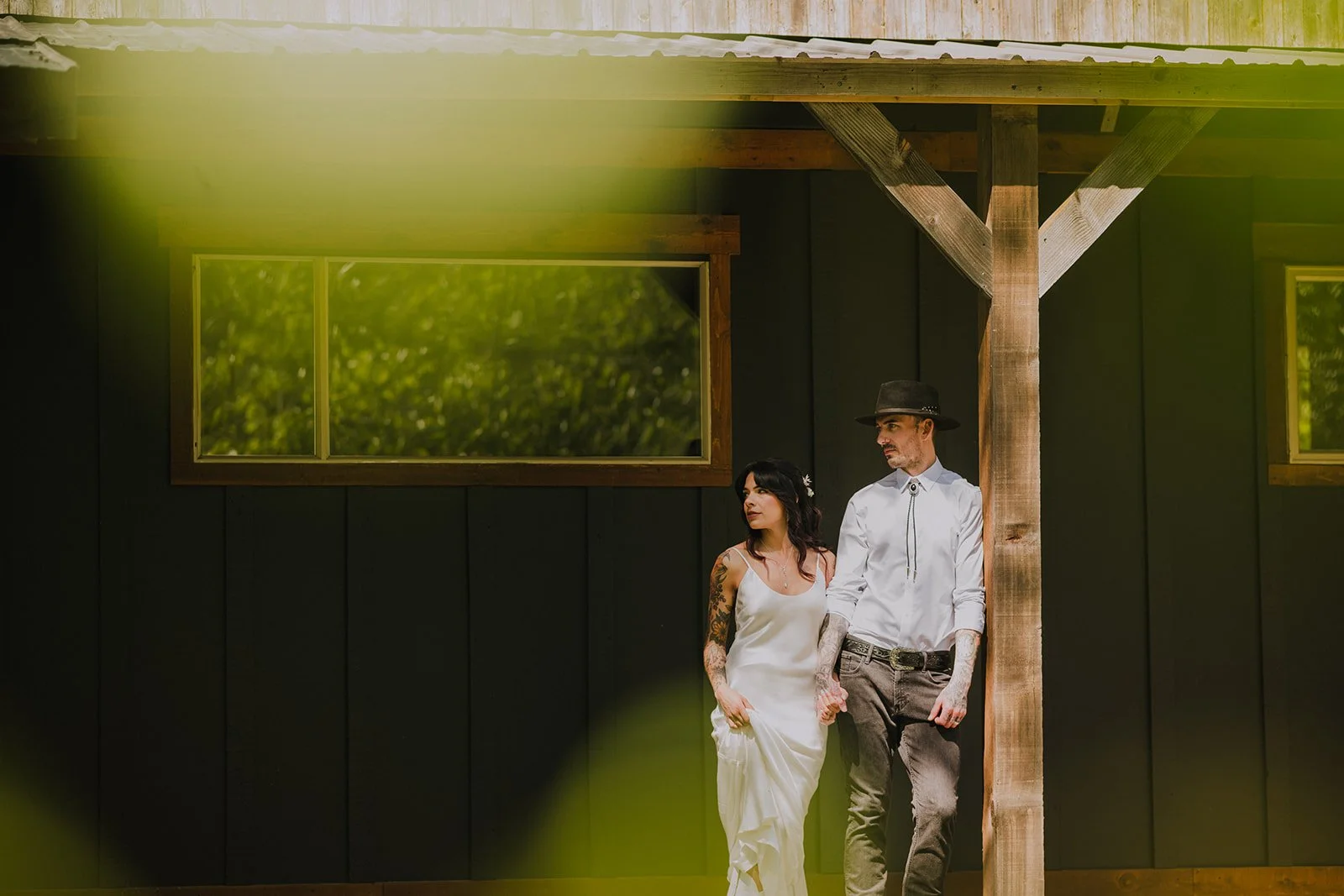  A bride and groom standing outside a cabin, looking to the side.  