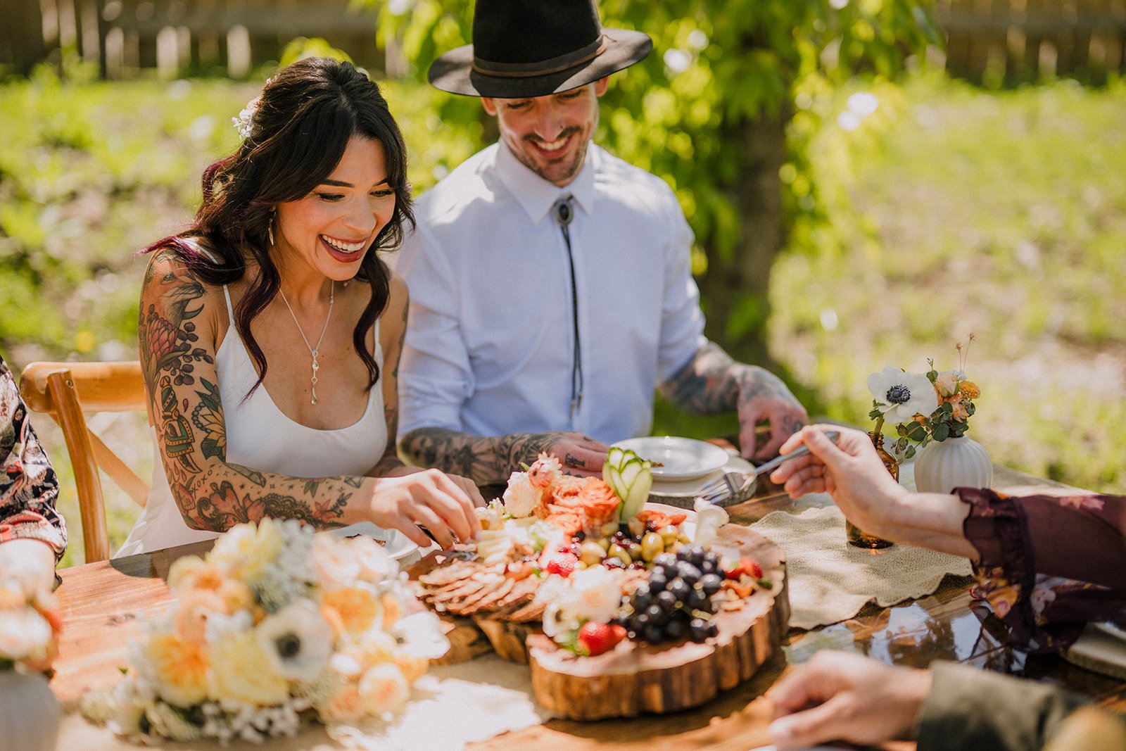  A bride and groom seated and enjoying a charcuterie board full of delicious food.  