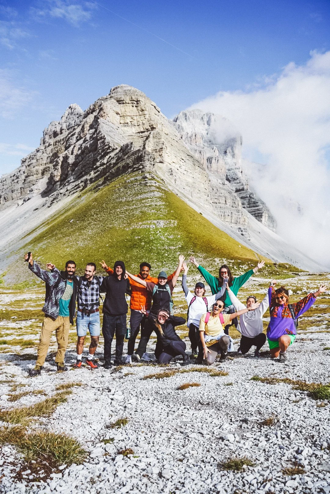 Group of people posing joyfully in front of a mountain under a blue sky.