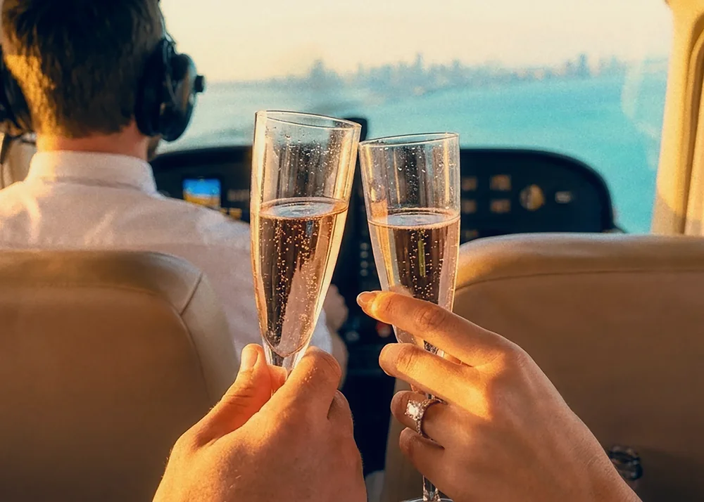 Couple toasting with glasses in the cabin during a sunset flight over Miami
