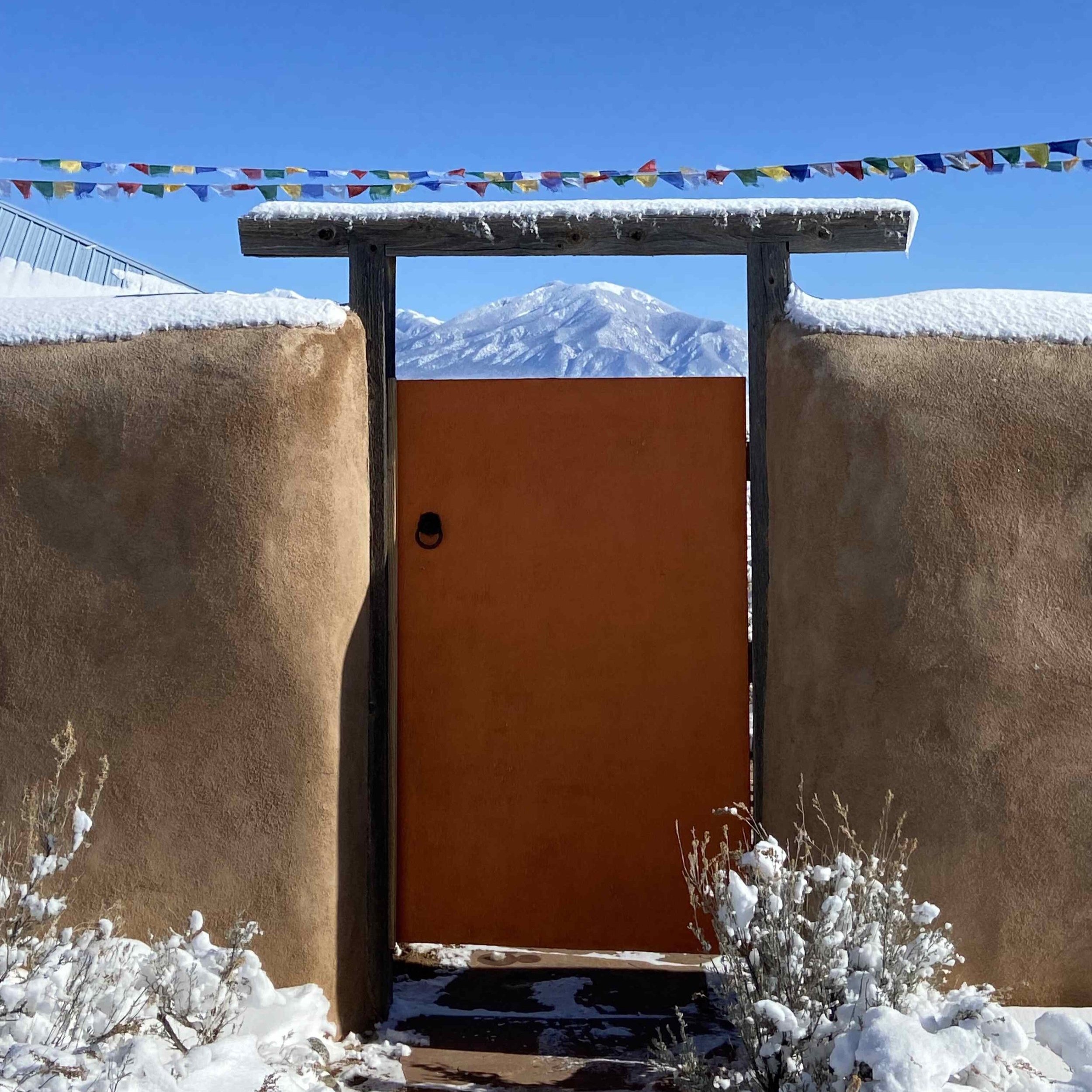 Orange gate, snow and Taos Mountain