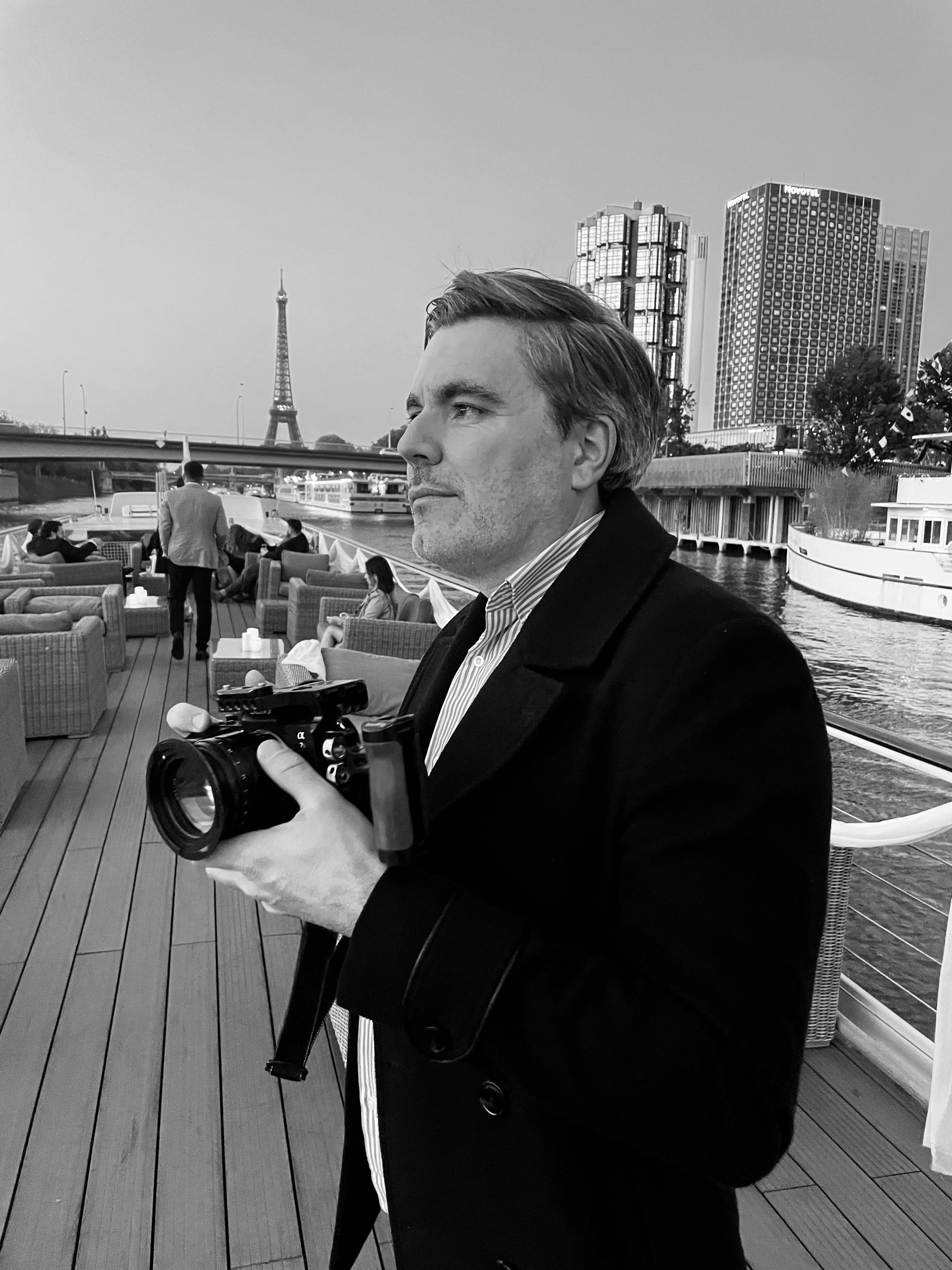 Man with camera on boat, Eiffel Tower and cityscape in background, Paris