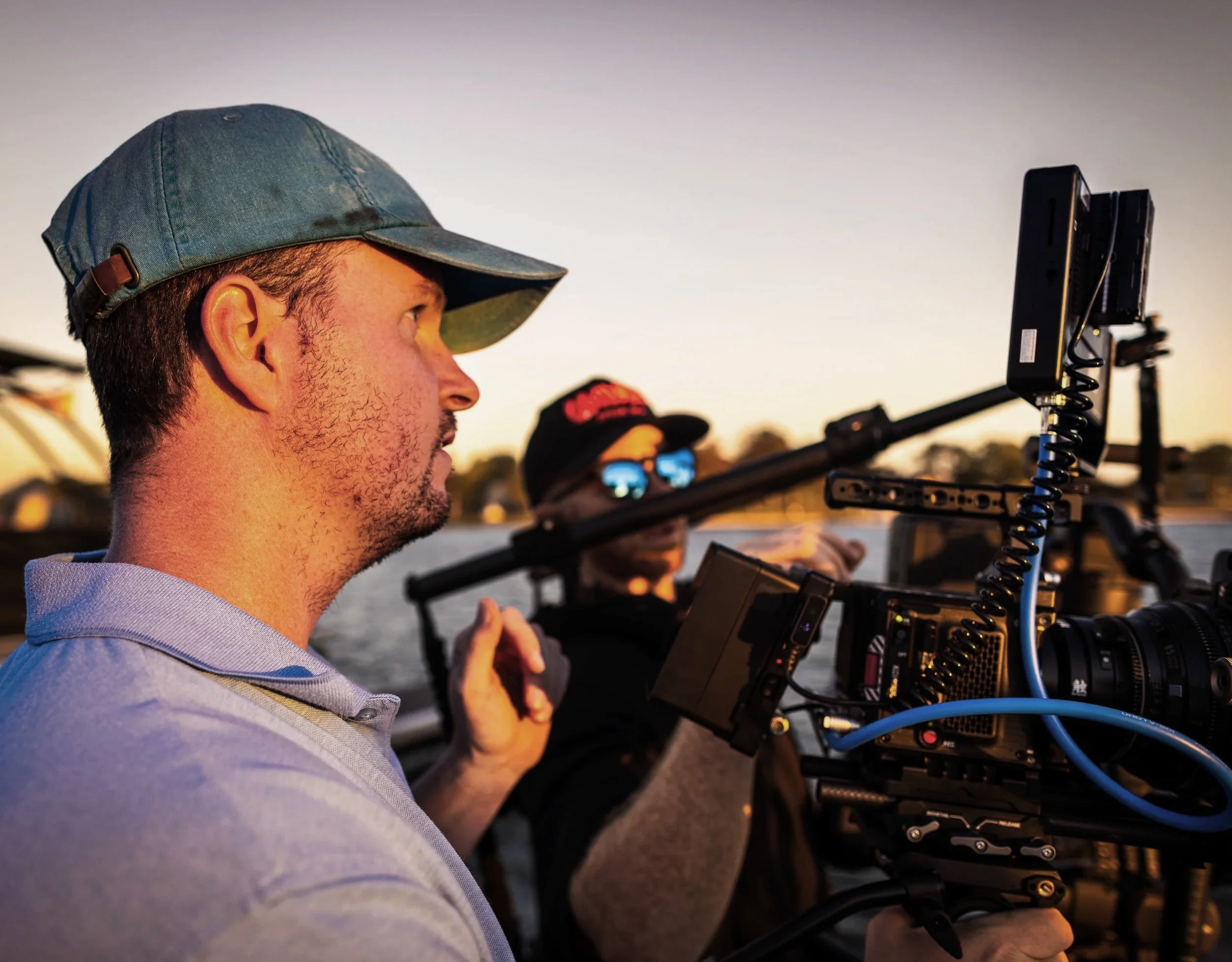 Cinematographer operating a professional cinema camera during an outdoor production at sunset.