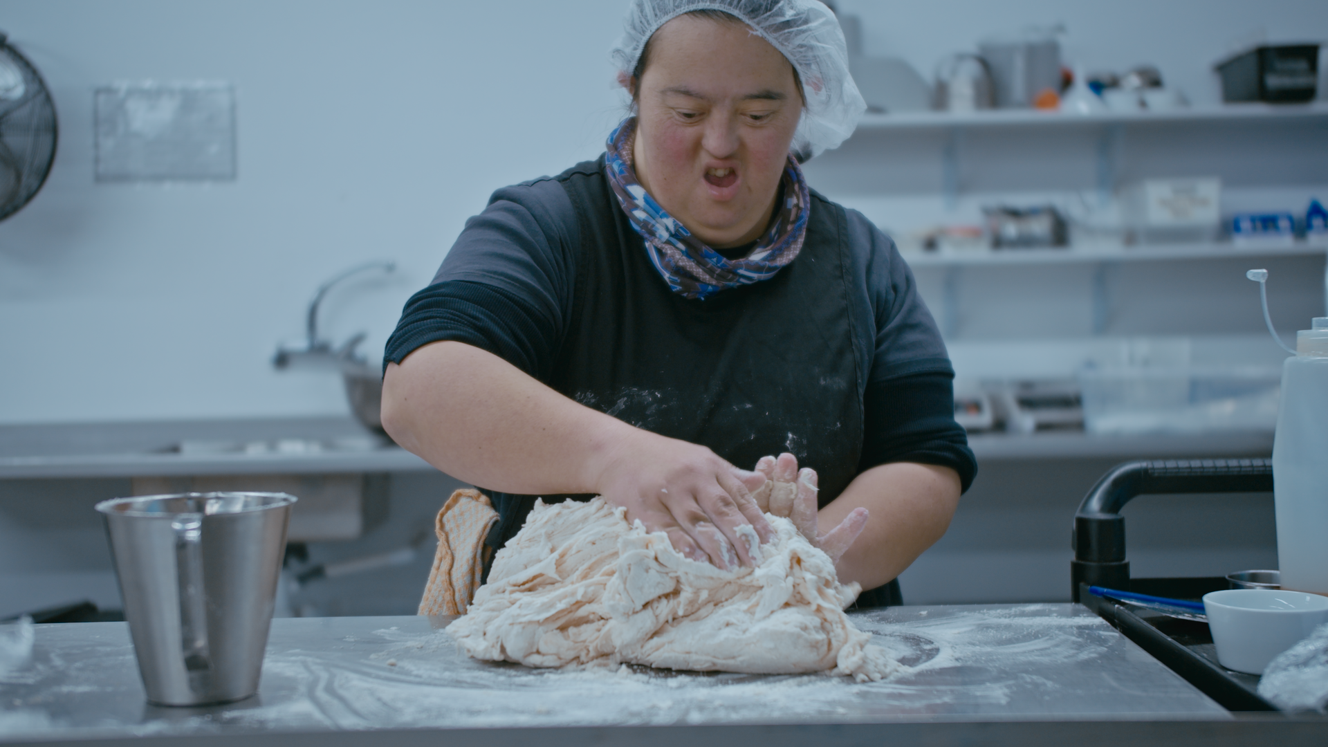 A young women kneads dough.