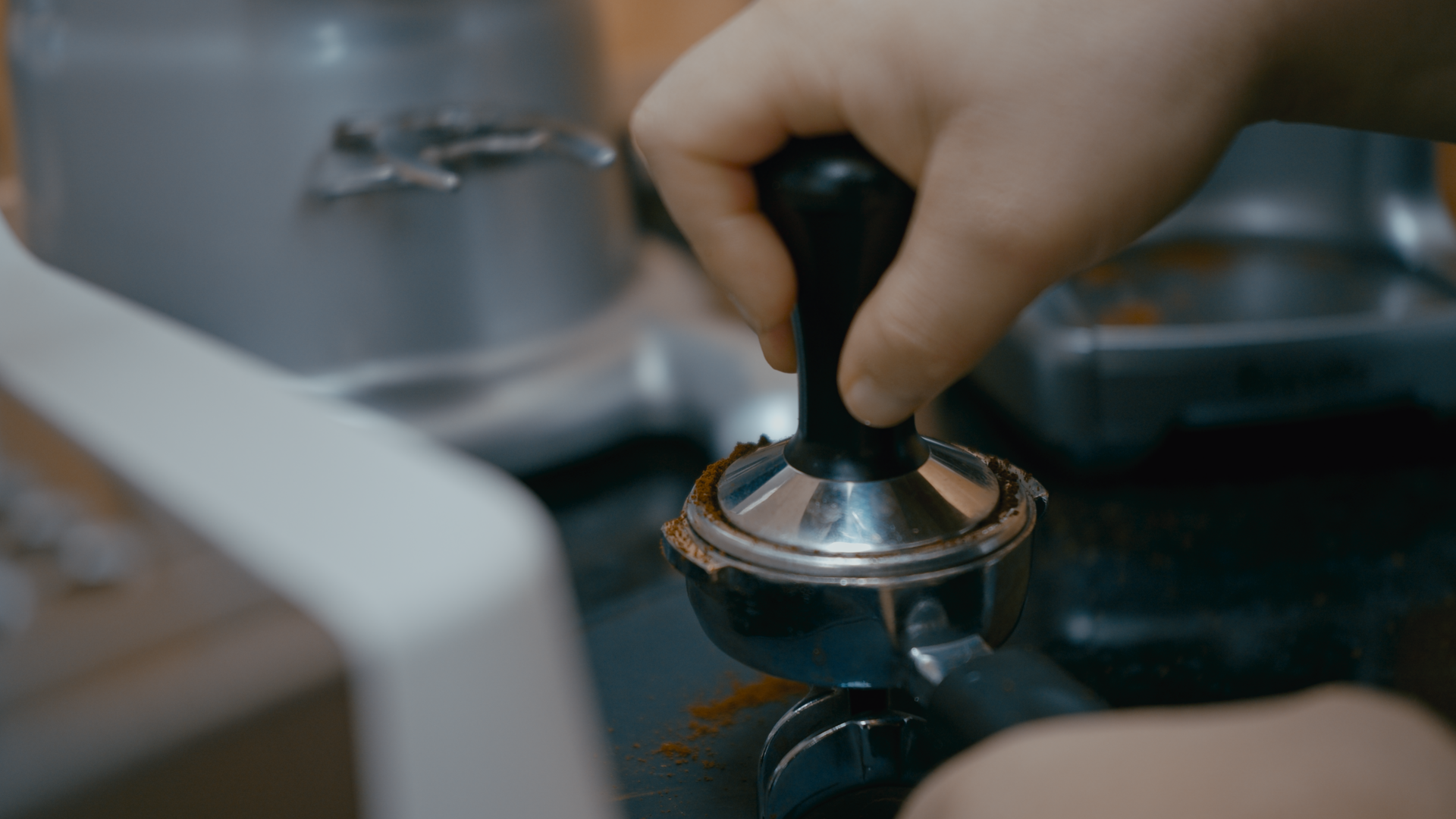 A hand tampers coffee.