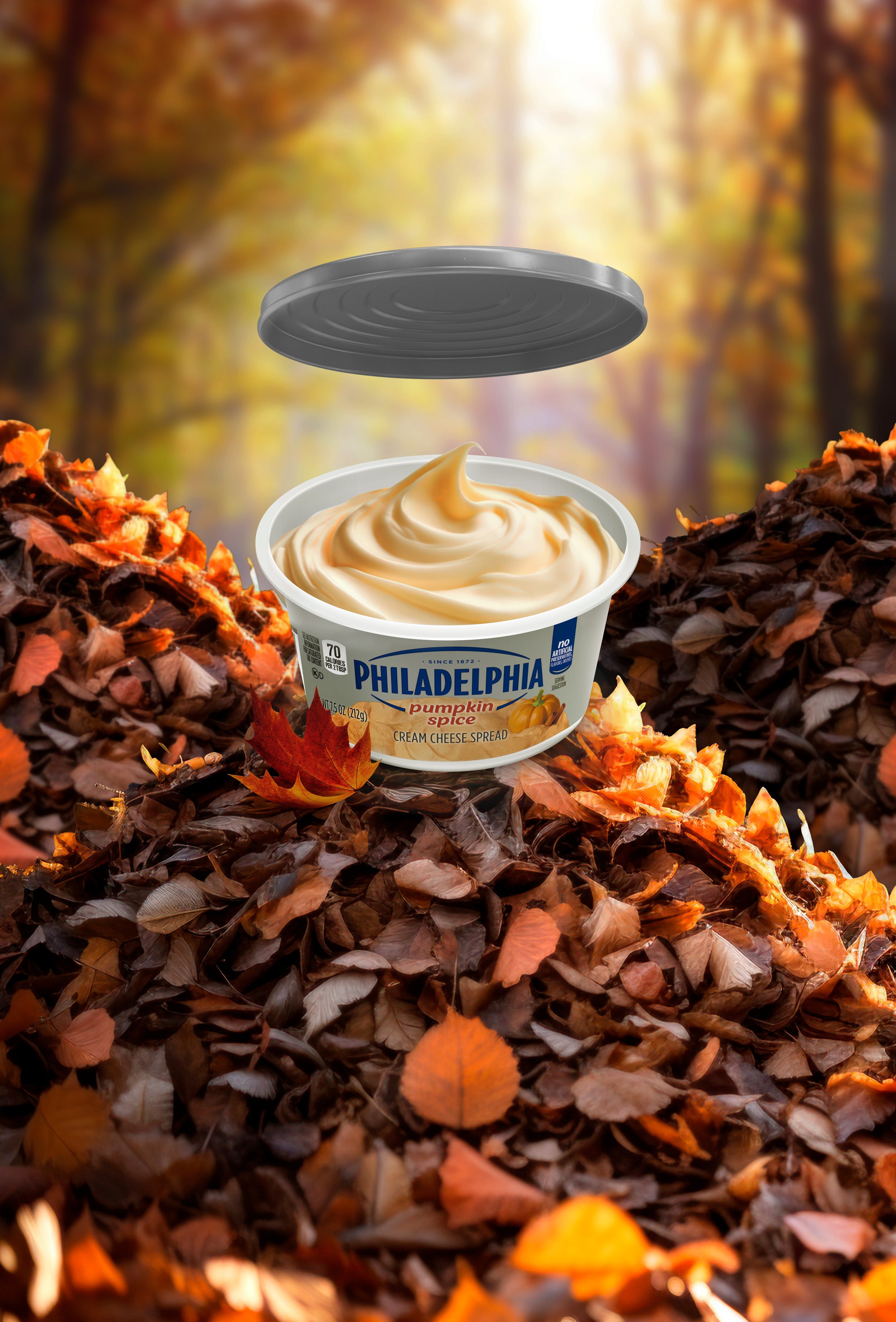 An open tub of pumpkin spice cream cheese sitting in a pile of fall leaves