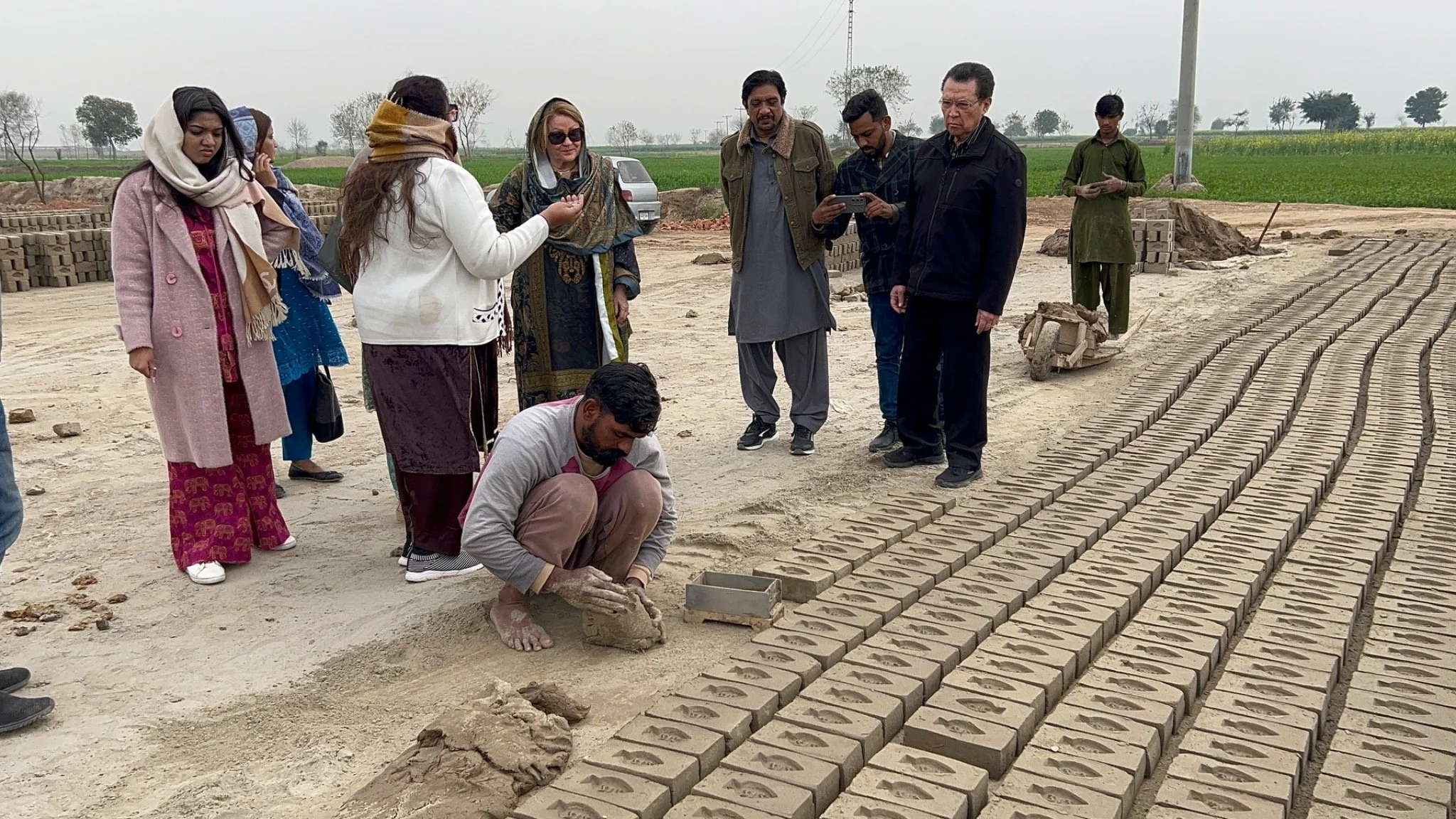 Dr. Patricia and Rev. Benjamin with the ministry team beside a worker making bricks at a kiln in Pakistan.