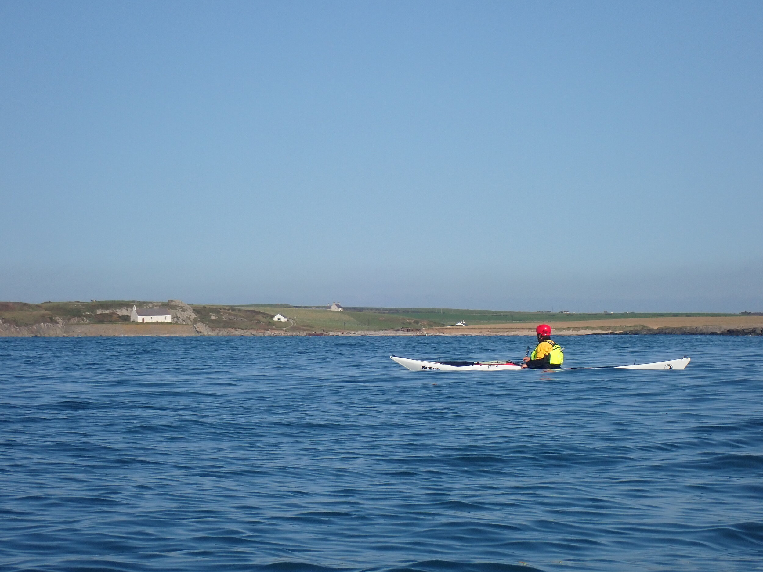 Sea kayaking past St Cwyfan's Church, Anglesey