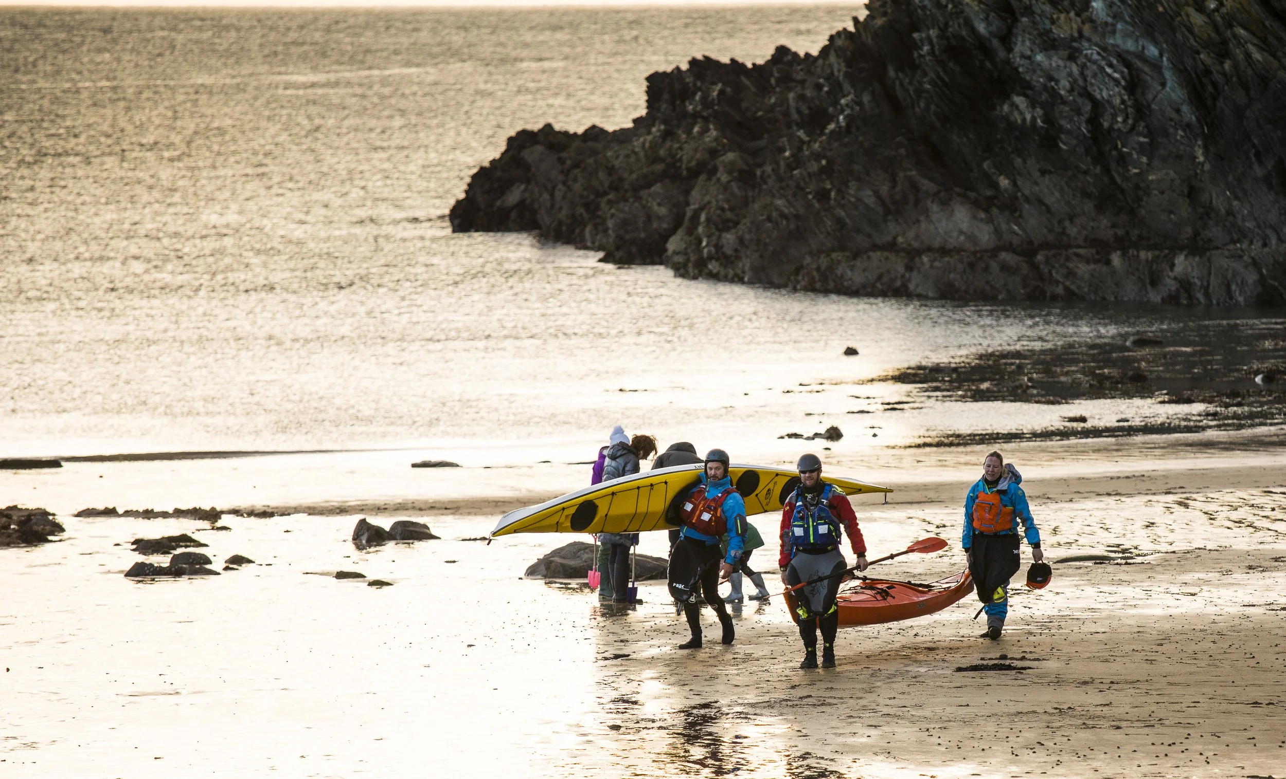 5 Kayakers coming back from a day with Sea Kayaking Wales on a beach on Anglesey