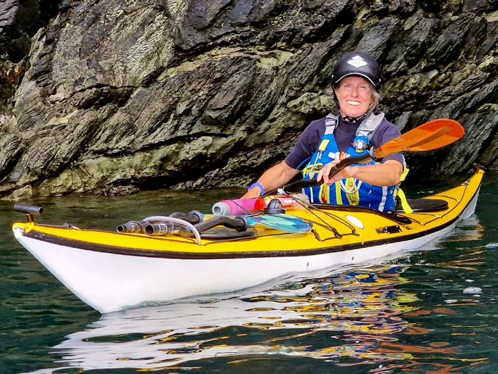 Woman in yellow and white kayak on sea working for Sea Kayaking Wales on Anglesey