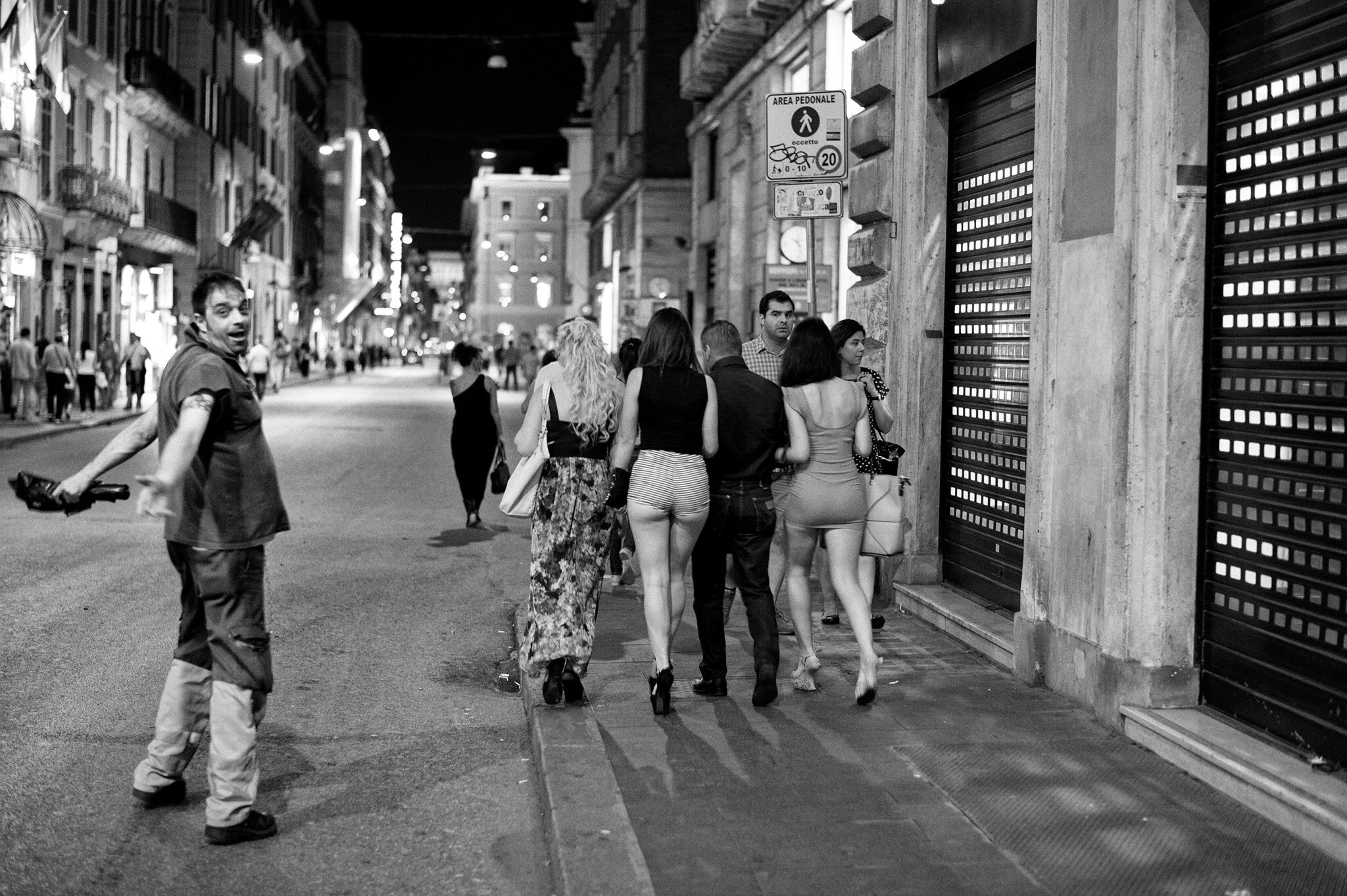 Street photography notturna in Via del Corso a Roma: un netturbino urla di stupore al passaggio di un gruppo di ragazze in abiti succinti