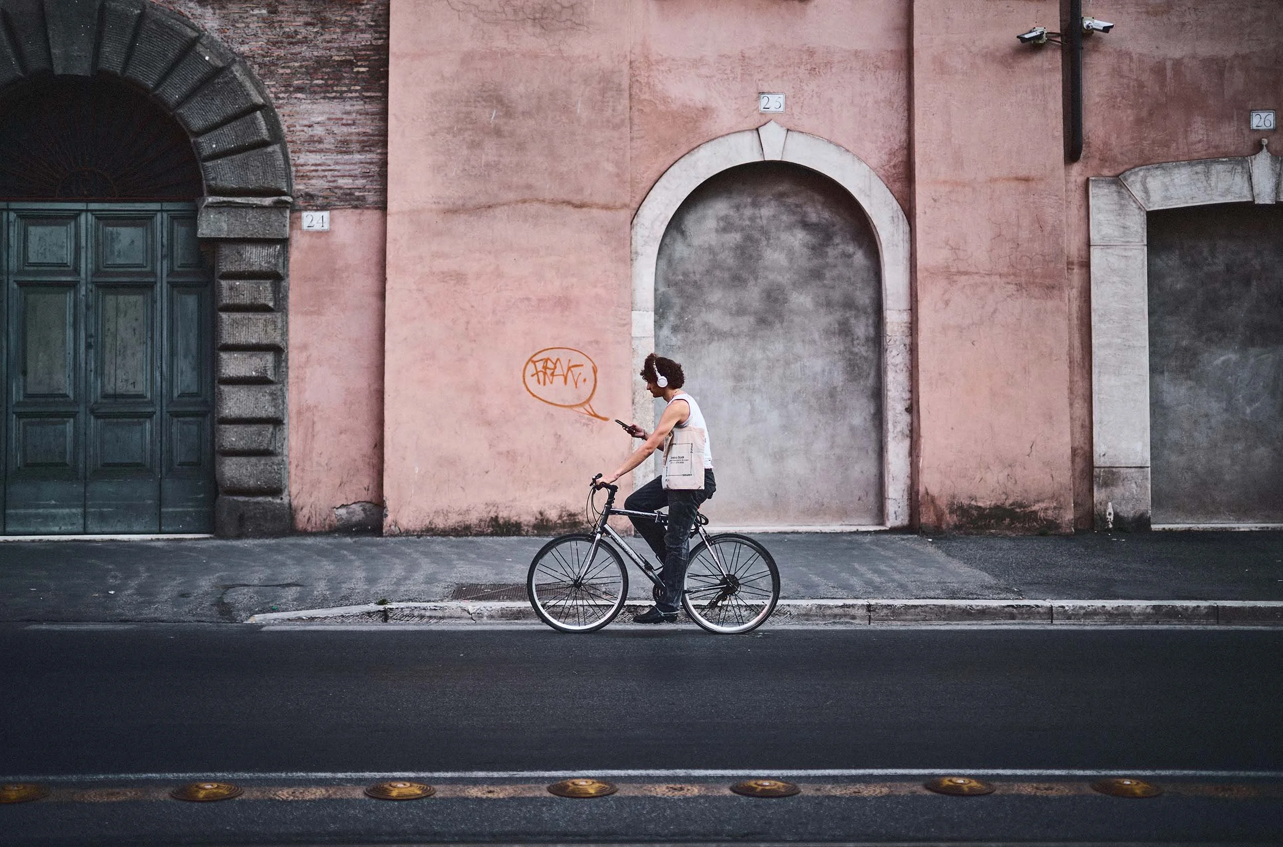Street photography Roma: composizione geometrica con ciclista e architettura urbana color pastello.