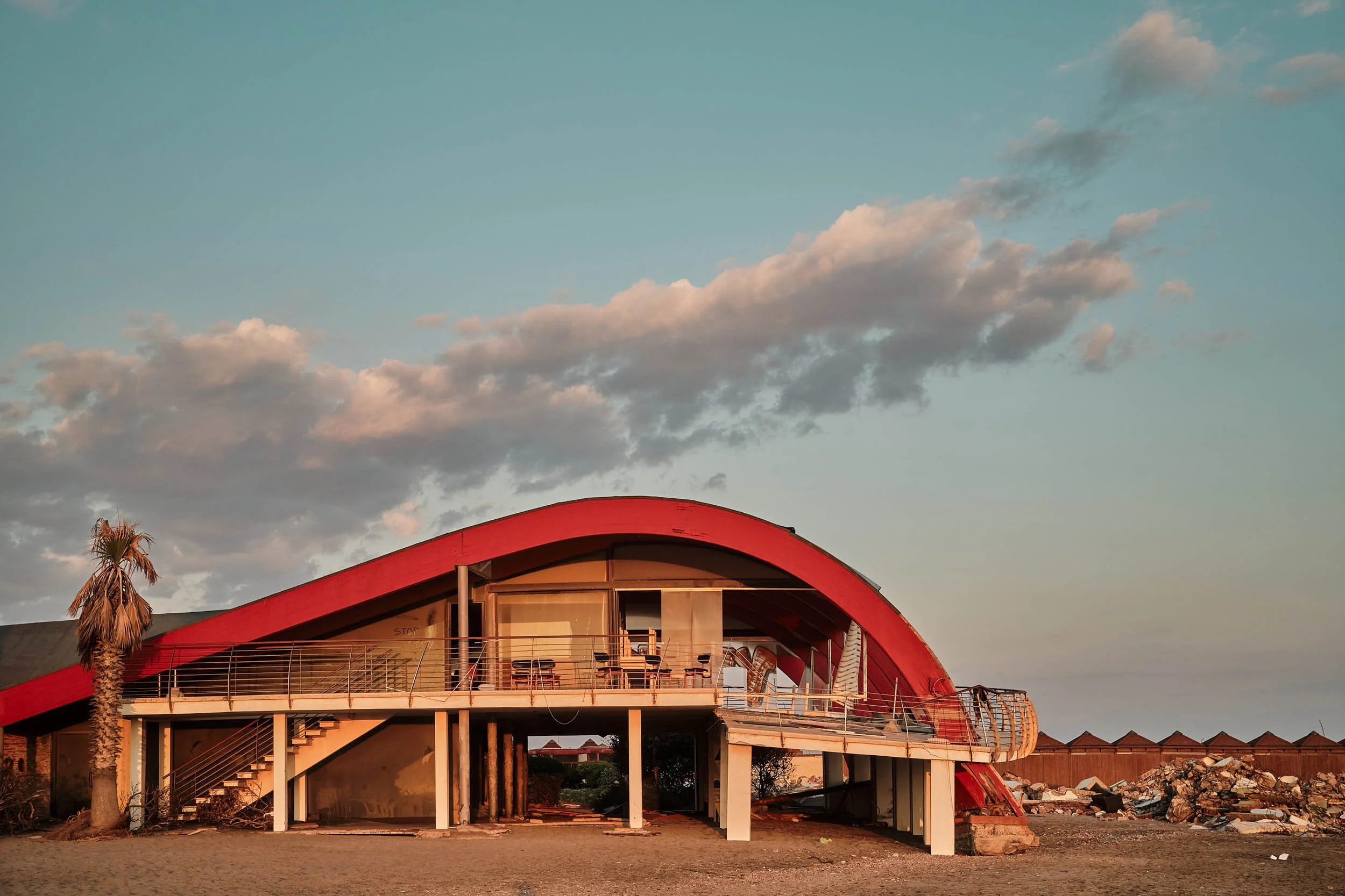 Veduta al tramonto dello Sporting Beach, Ostia. Un brutale contrasto tra la bellezza della luce calda del tramonto, la bellezza dell'architettura e il degrado della distruzione della struttura, con cumuli di macerie  e il terrazzo a sbalzo spezzato