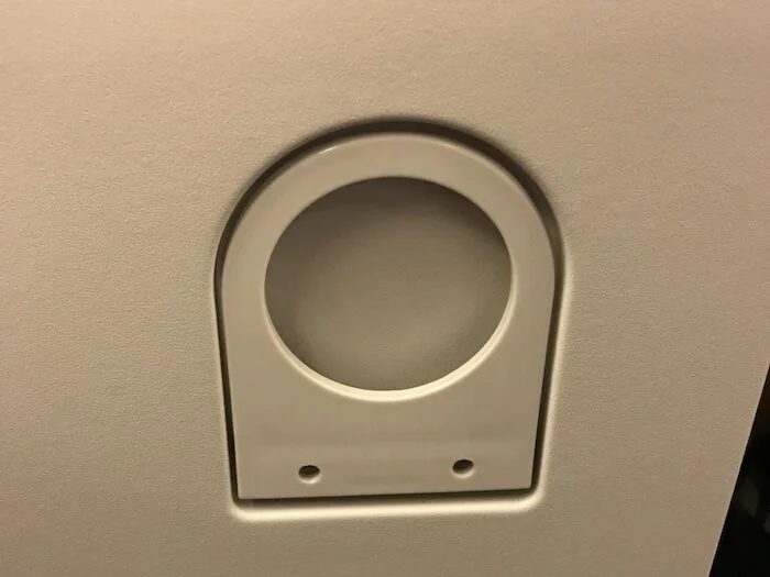 Stowed tray table with embedded cupholder folded up.