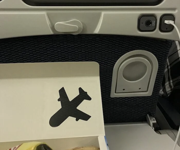 Picture of the lowered tray table with the stowed cup holder embedded in the seat in front of me.