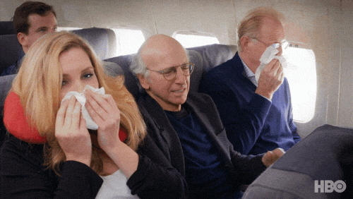 GIF of a man trapped in middle seat of an airplane between two visibly sick people. (credit: giphy.com)