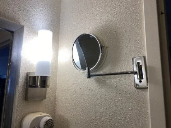 Image of the two-sided mirror attached to a metal arm that’s been drilled into the wall.