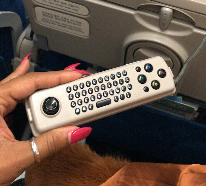 Image of me holding a remote/game controller for the my screen on the plane.