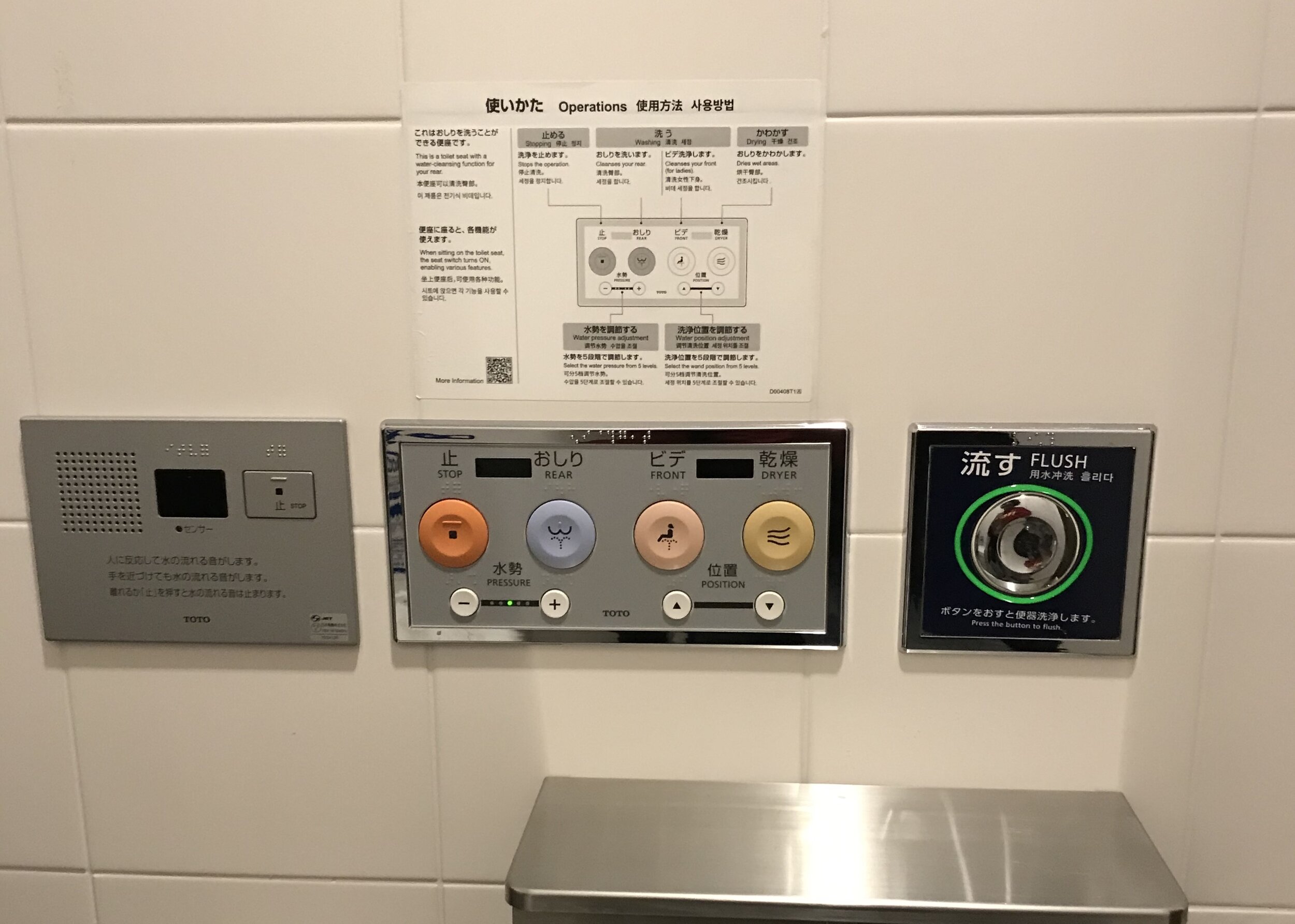 Pictured here [left to right], is an audio panel of some sort (with only Japanese writing), a bidet control panel with different colored buttons (with icons) for different functions and an operations sign with instructions on how to use the bidet pa…