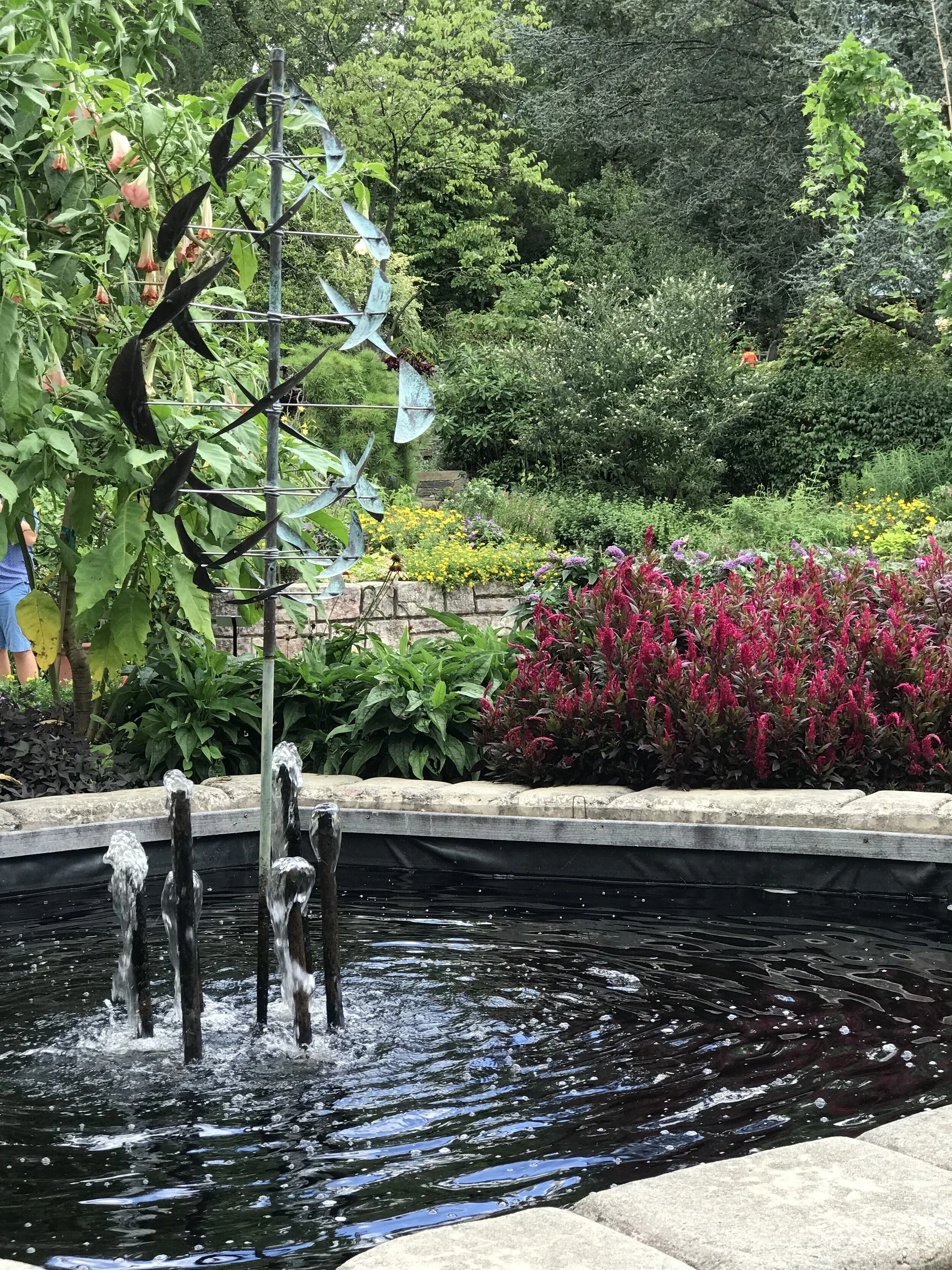 Picture of red fragrant flowers behind a flowing water fountain.