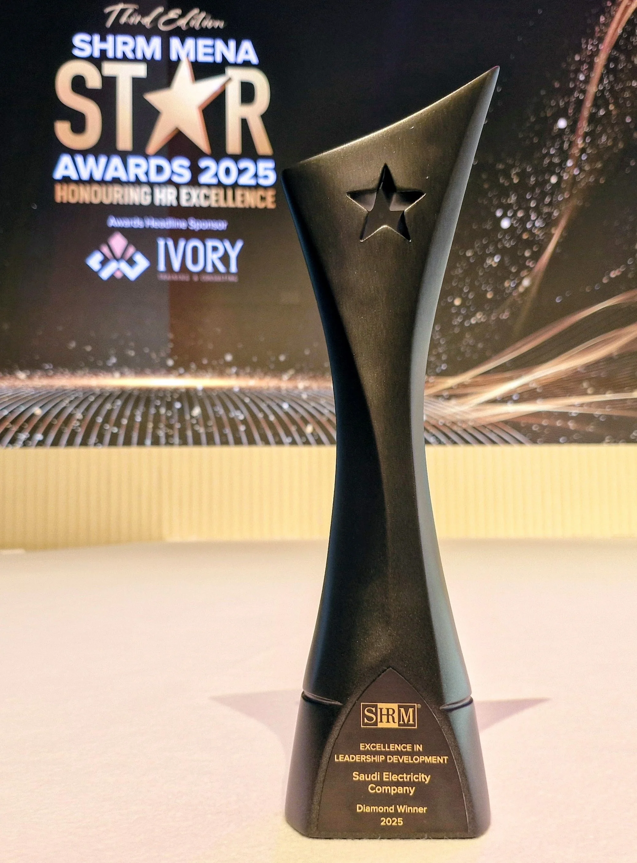 An award trophy with a star-shaped cutout and the logo SHRM, presented for excellence in leadership development, awarded to Saudi Electricity Company in 2025.