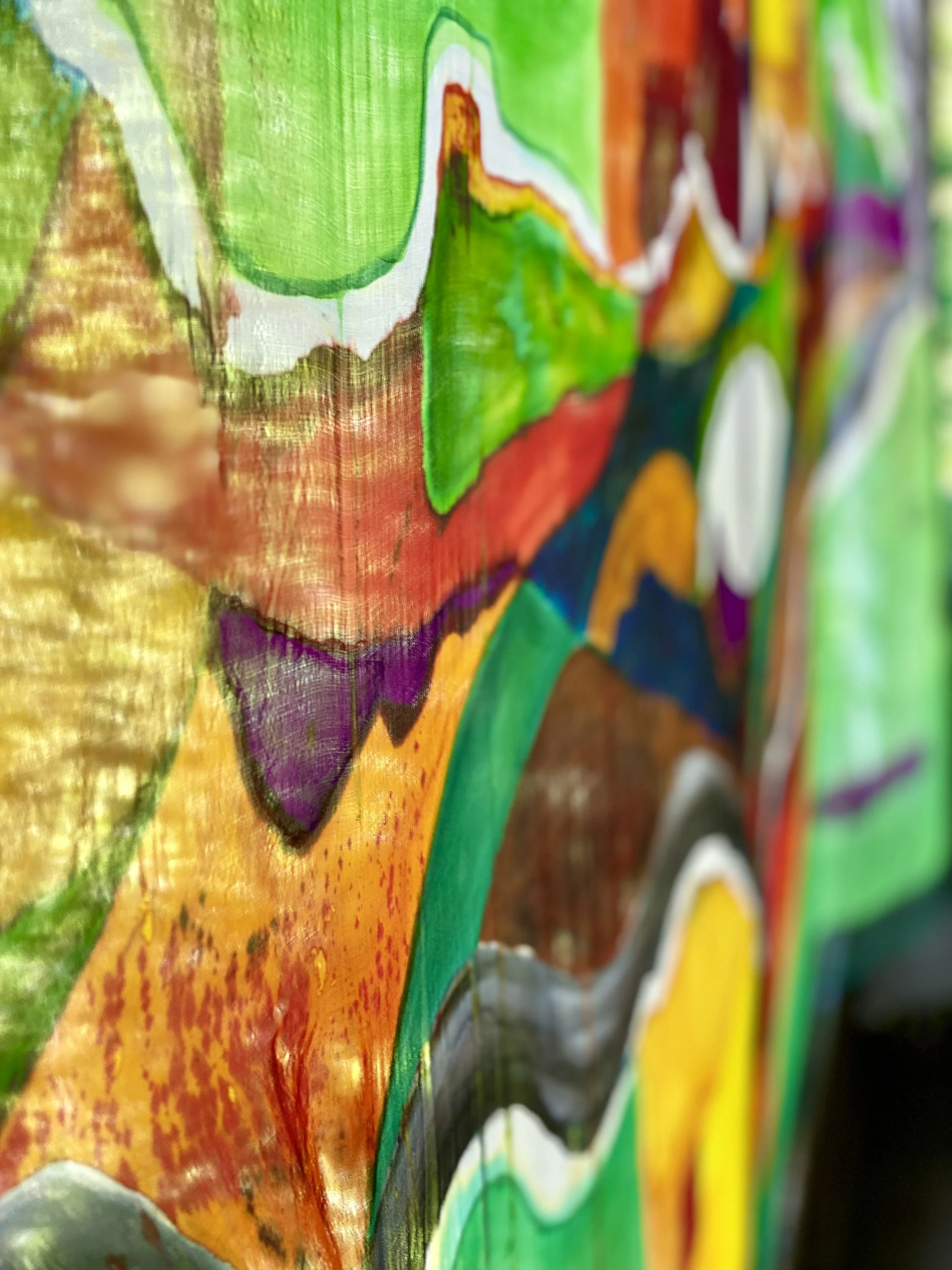 Close-up of a colorful abstract painting with vivid green, orange, yellow, purple, black, and white sections, and visible textured brushstrokes.