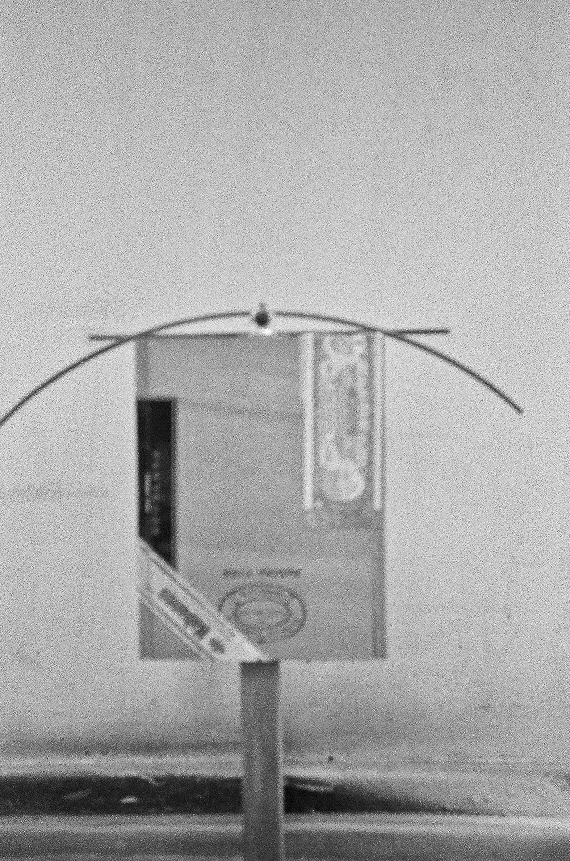 A small frozen pipe sprouting from the ground with a box surrounding it, with a blurry horizon in the background.