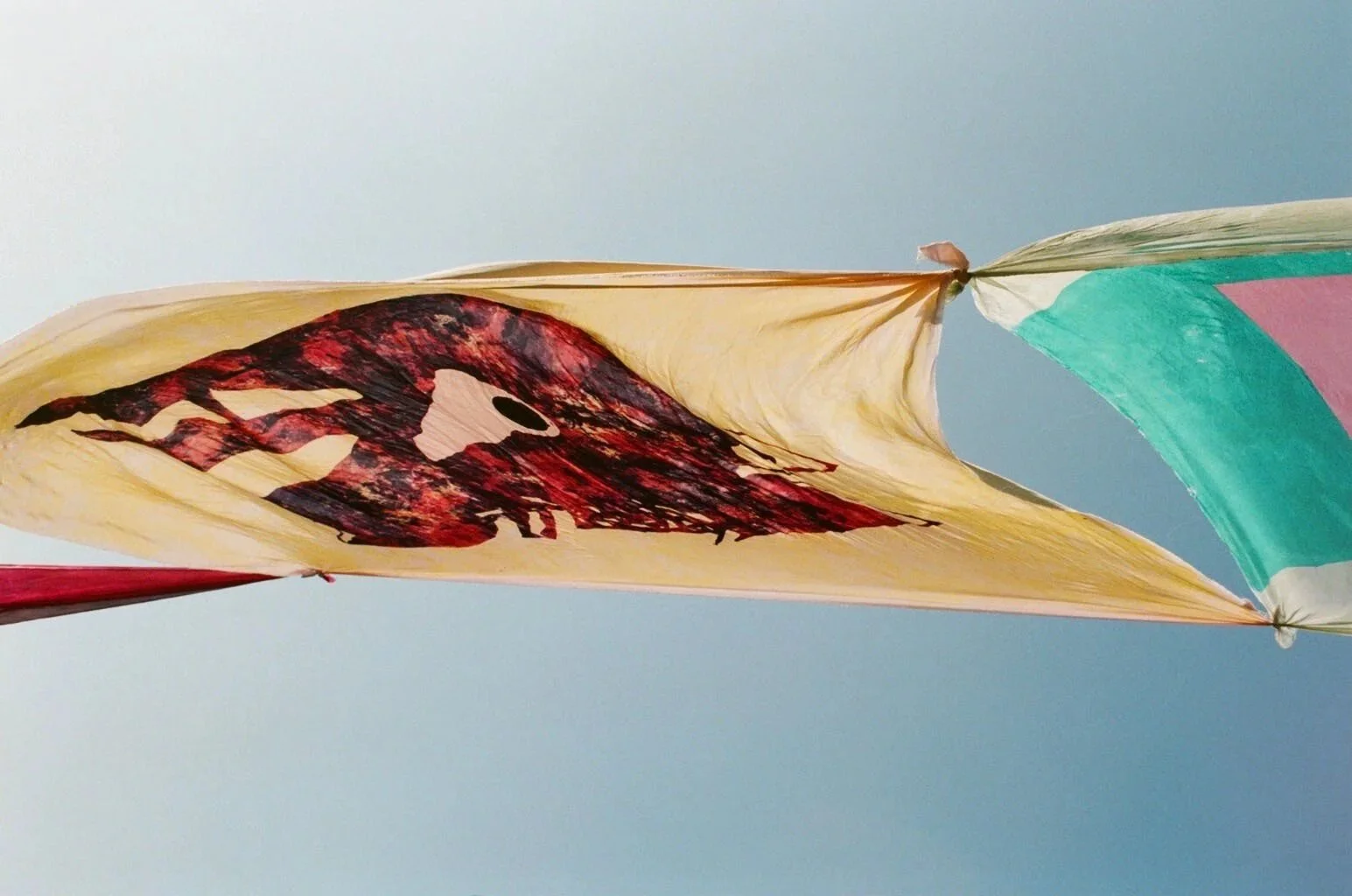 A colorful kite with a skull design flying in a clear sky.