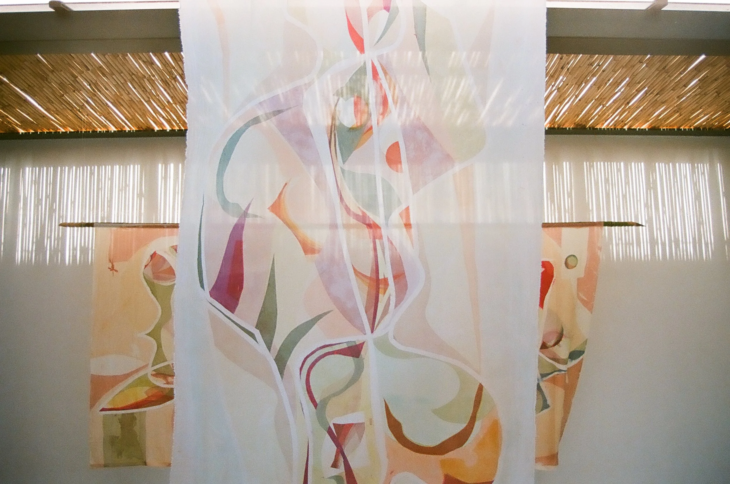 A colorful abstract painting of a woman, hanging from a ceiling with wooden beams and white vertical slats.